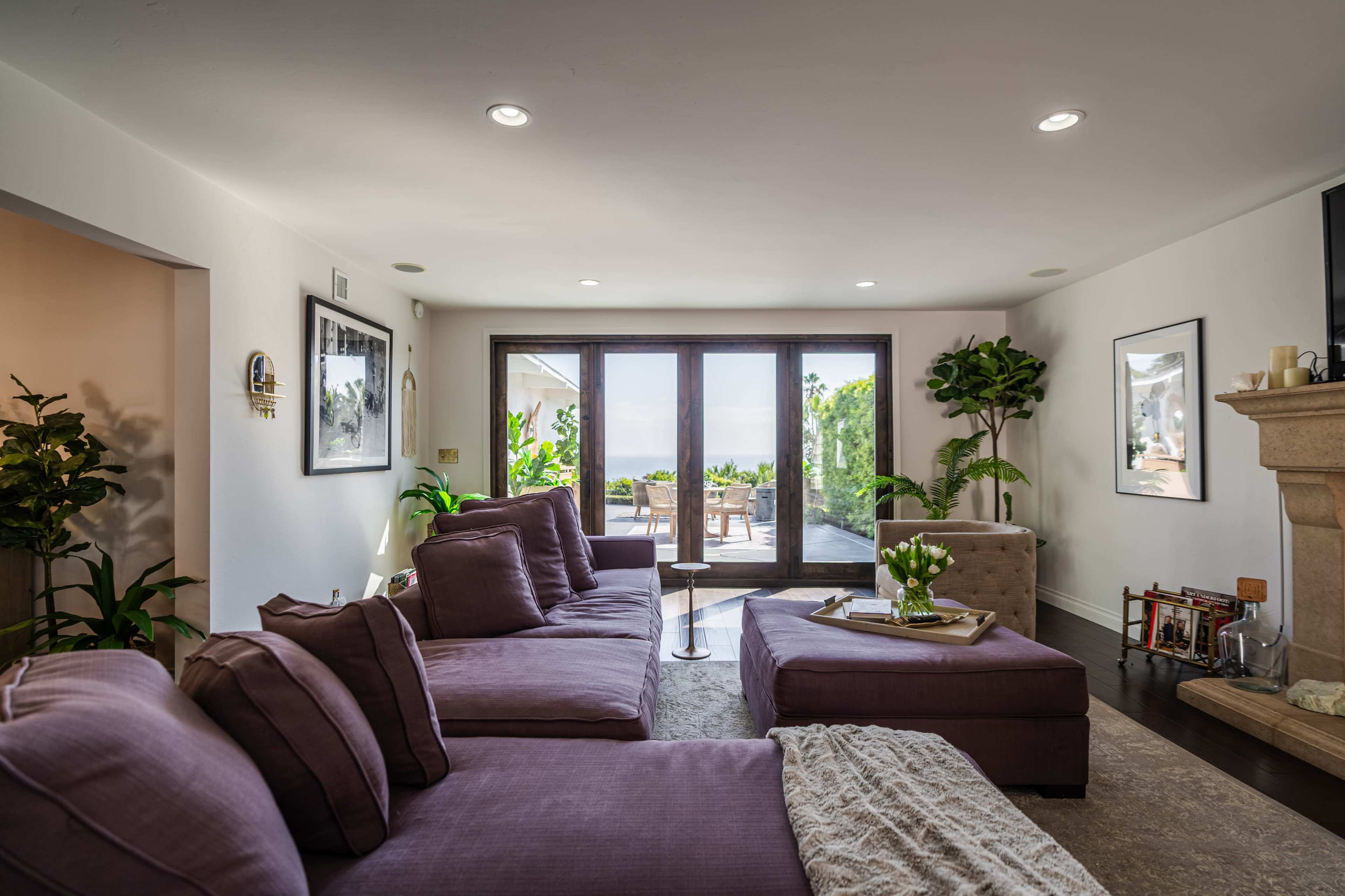 A modern living room features a large sectional sofa and a view of an outdoor patio through expansive glass doors.