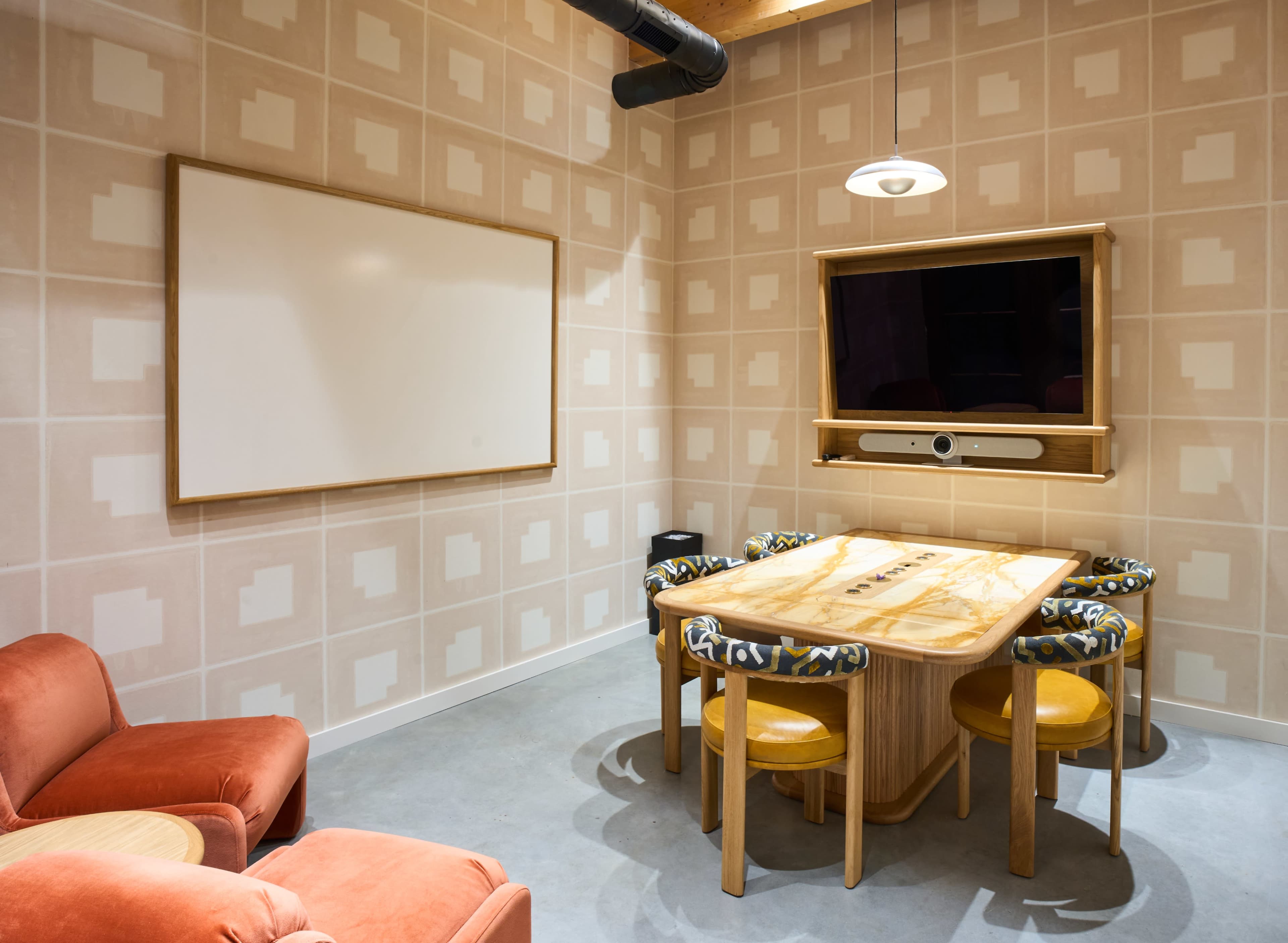 A conference room features a wooden table surrounded by six chairs, a whiteboard on one wall, and a mounted television on another.