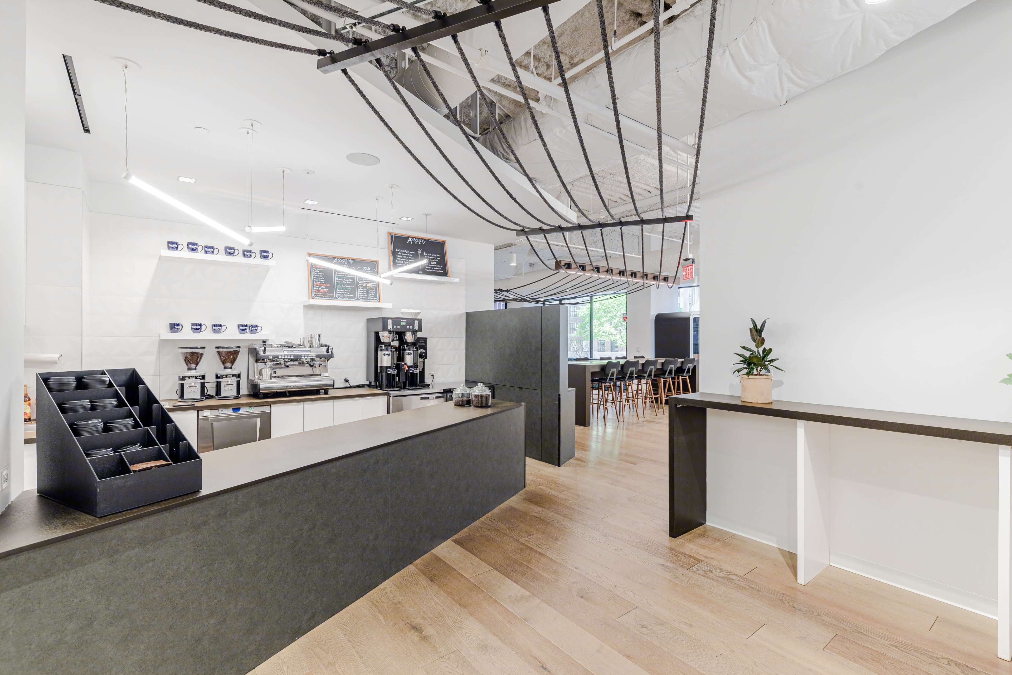A modern coffee shop interior with a sleek counter, coffee-making equipment, and a seating area in the background.