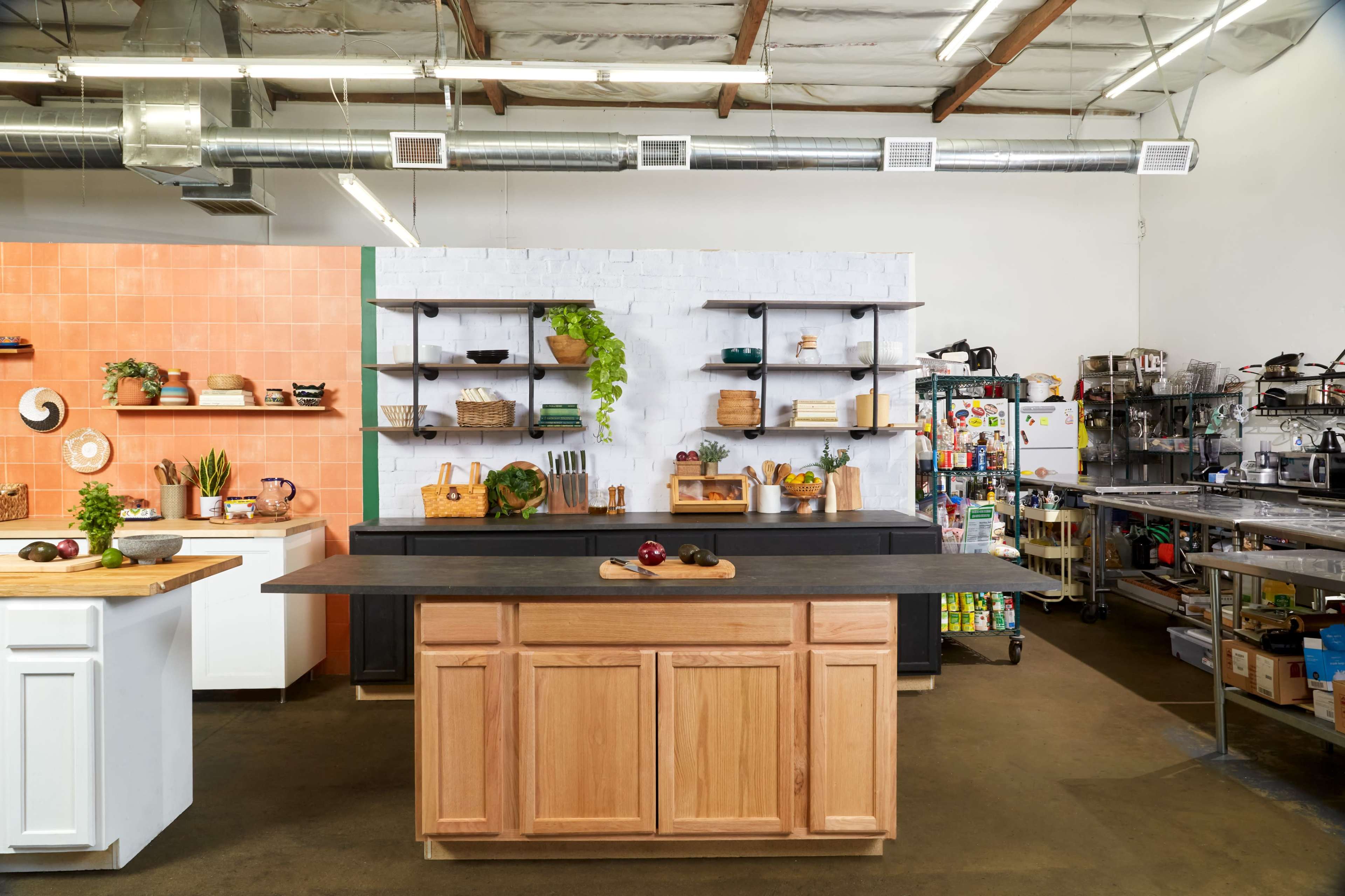 A modern kitchen with a central island, open shelving, and stainless steel appliances in a spacious, well-lit environment.