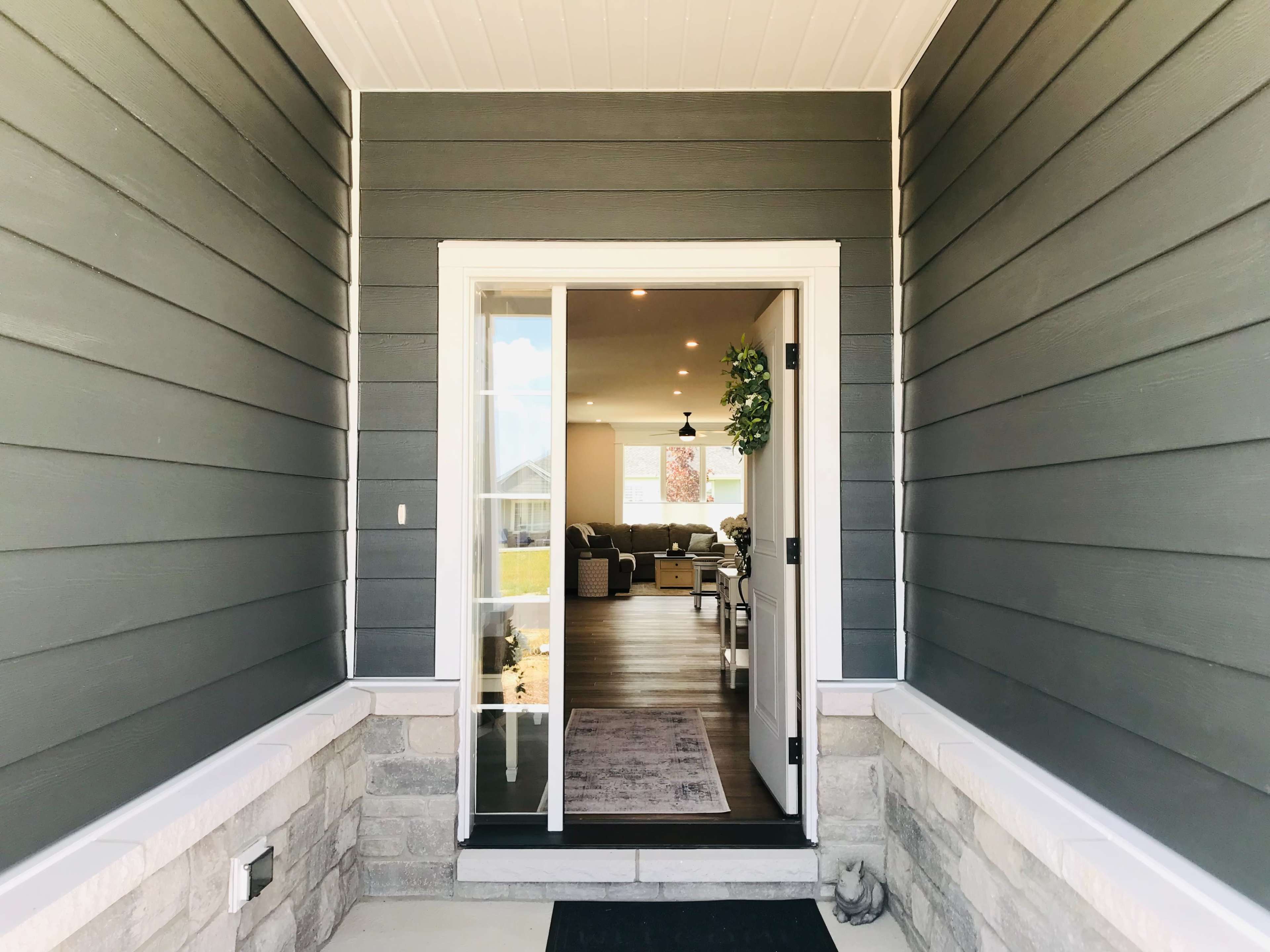 An open front door leading into a modern living space with visible furniture and décor.