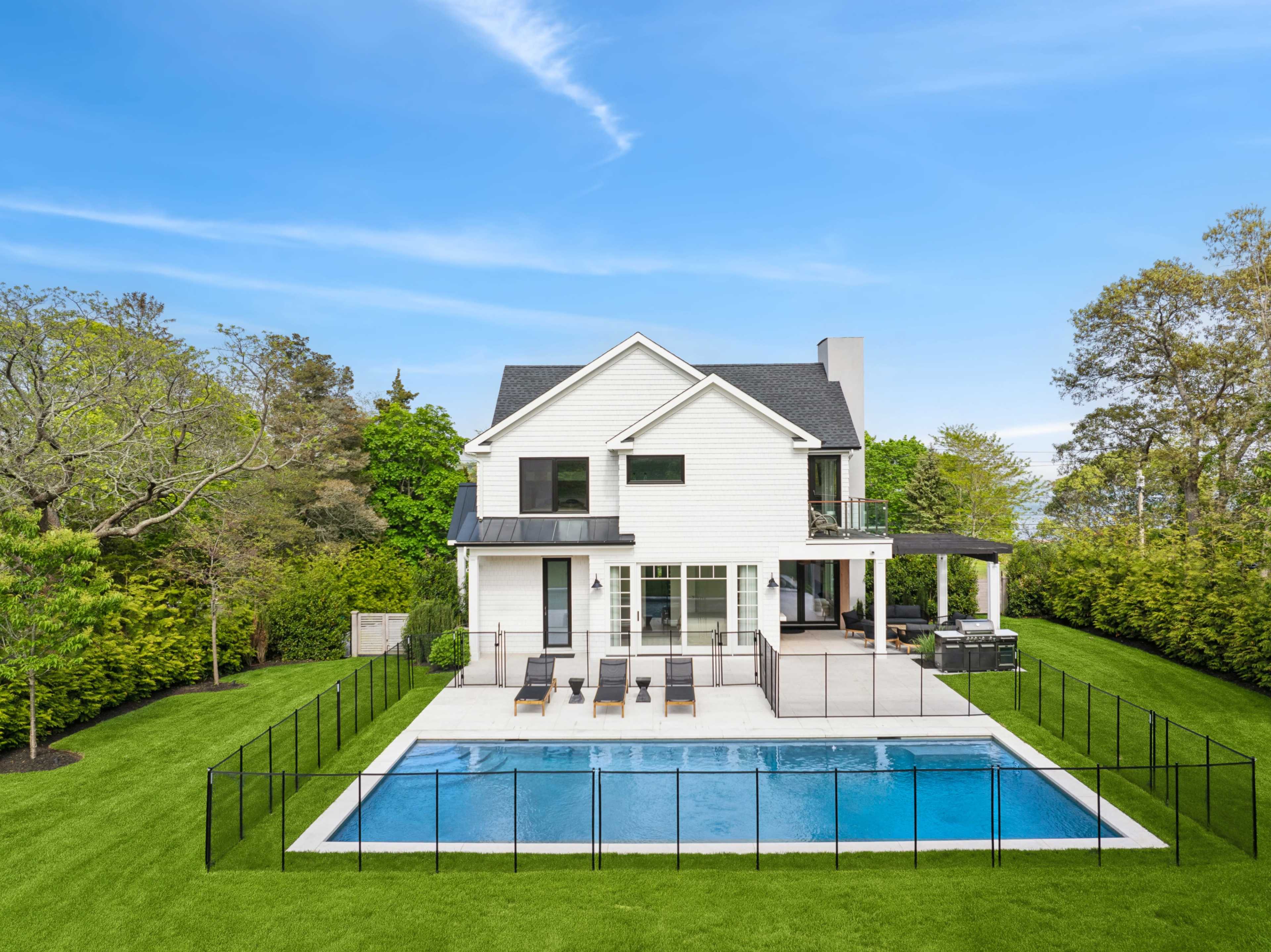 A modern house with a swimming pool and patio surrounded by lush greenery.