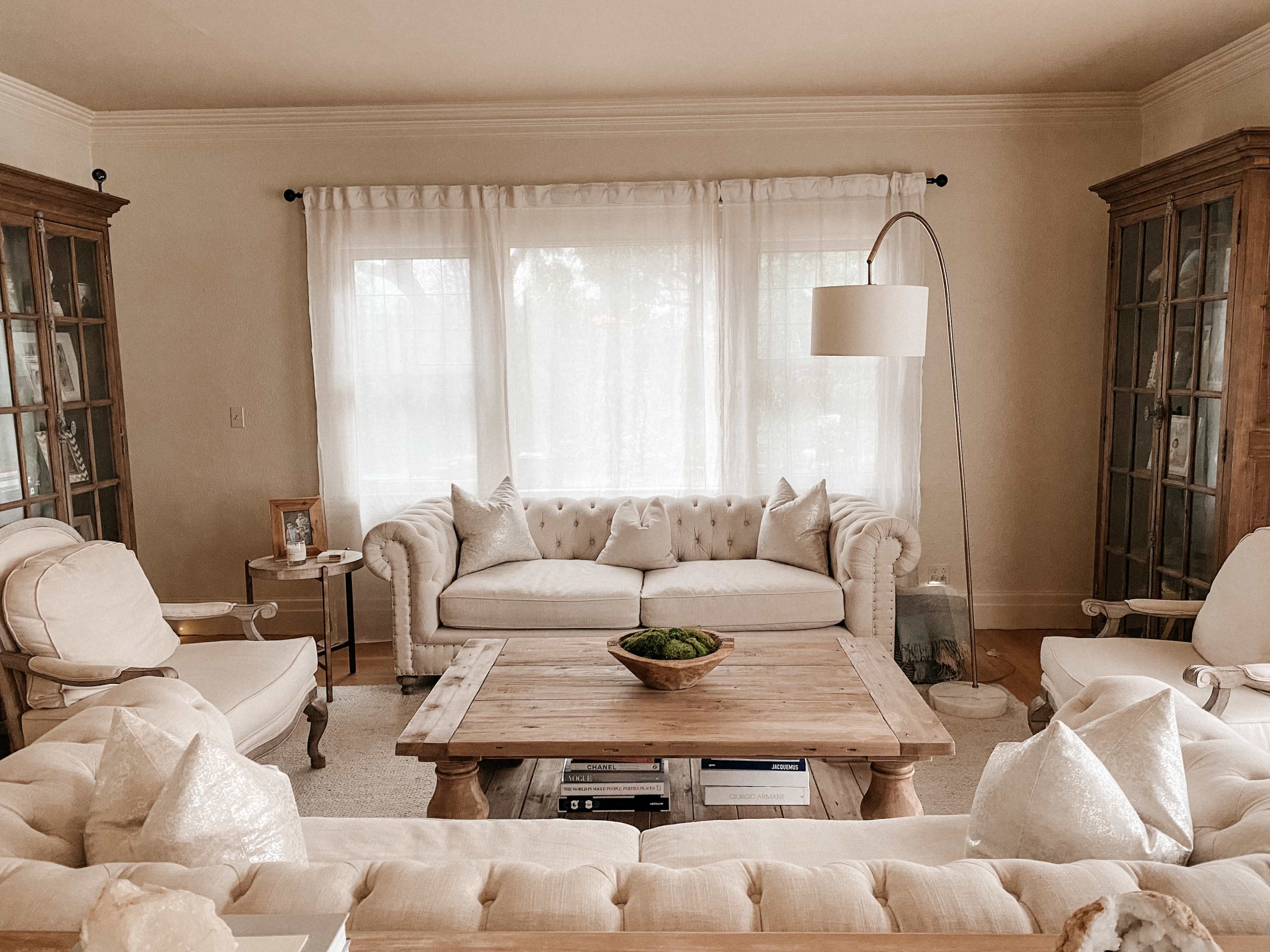 A cozy living room with a light-colored sofa, armchairs, a wooden coffee table, and glass-front cabinets.