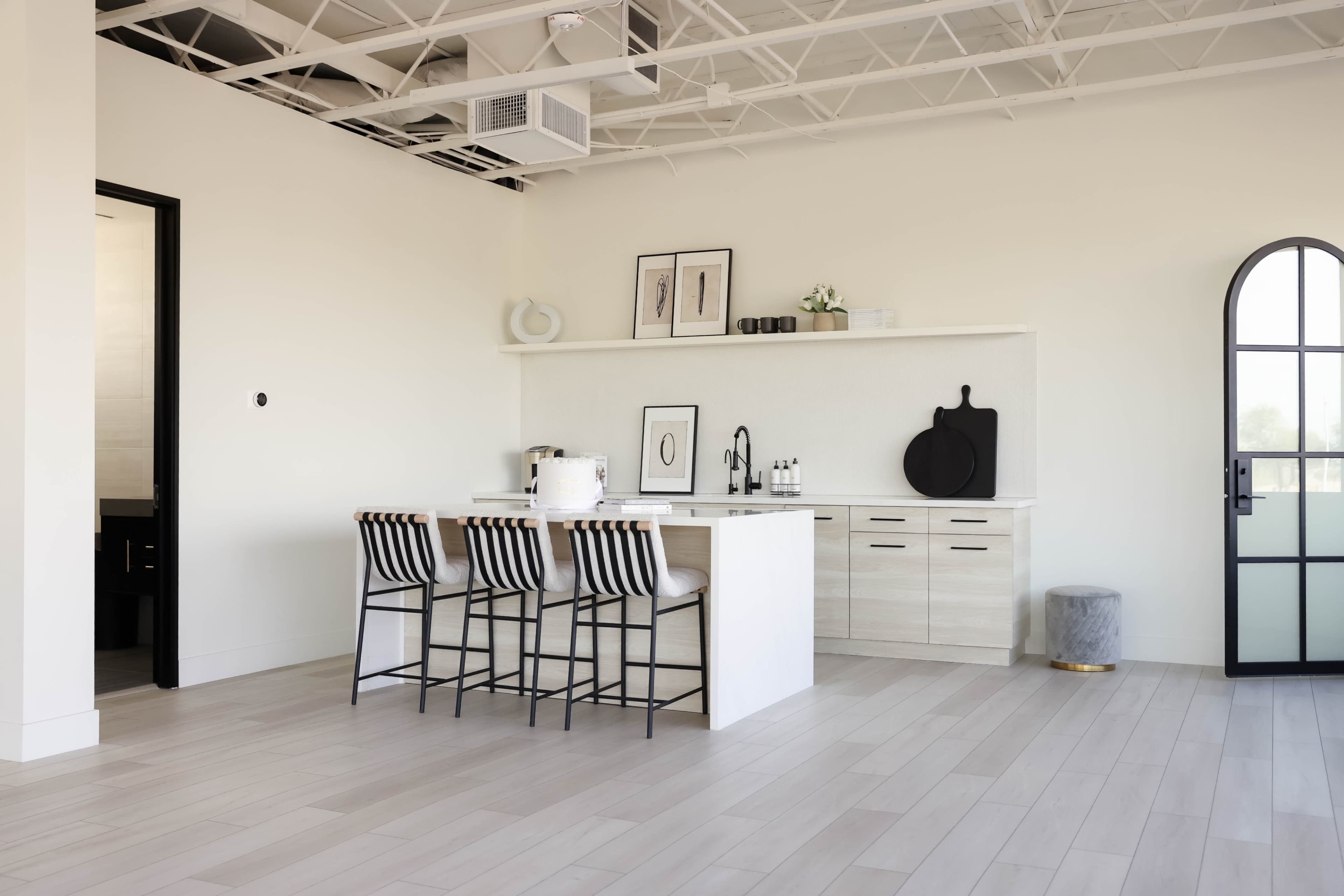 A modern kitchen features a central island with bar stools, sleek cabinetry, and a gray accent wall.