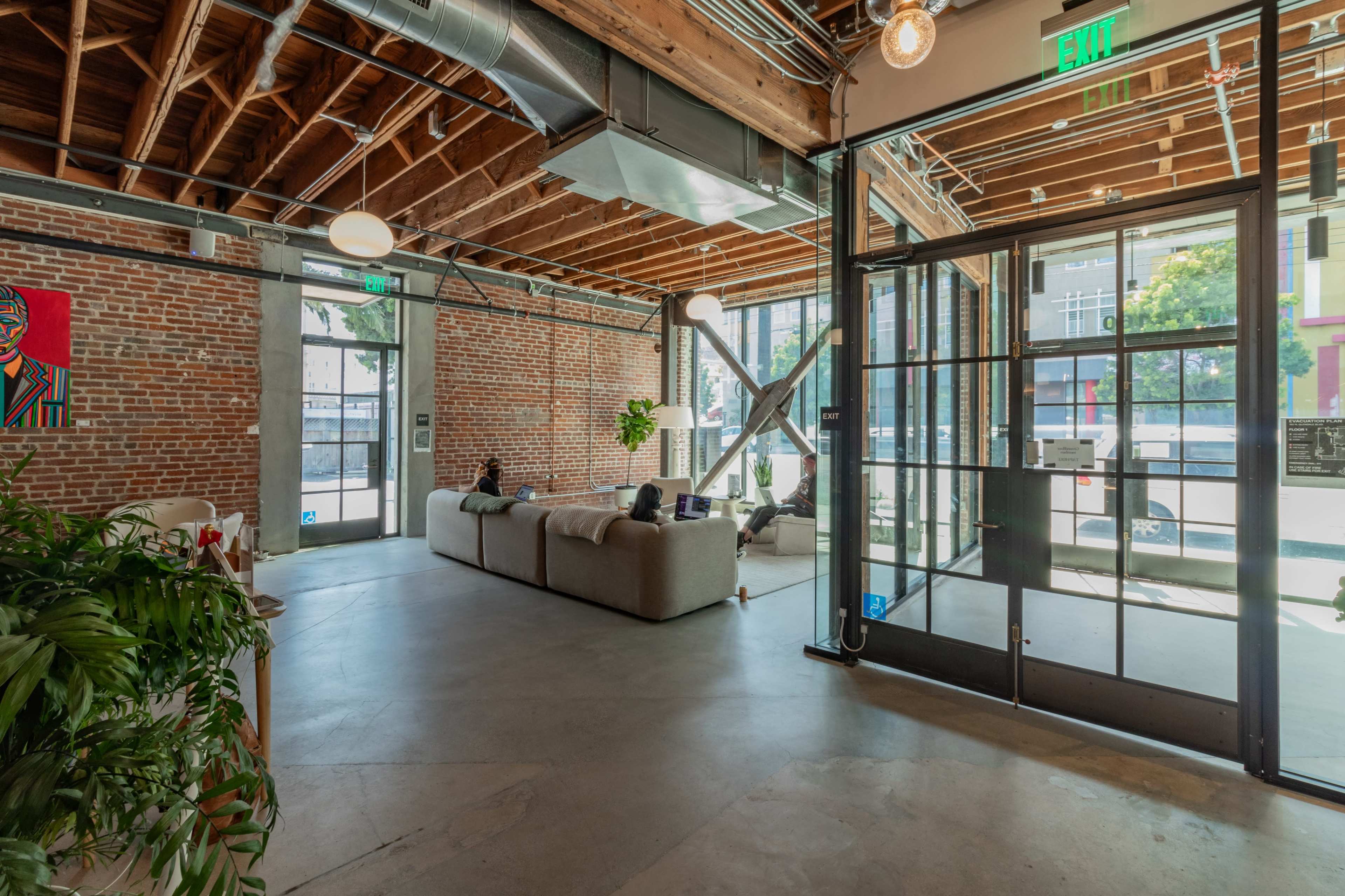A spacious interior with exposed brick walls, large windows, and modern furniture.