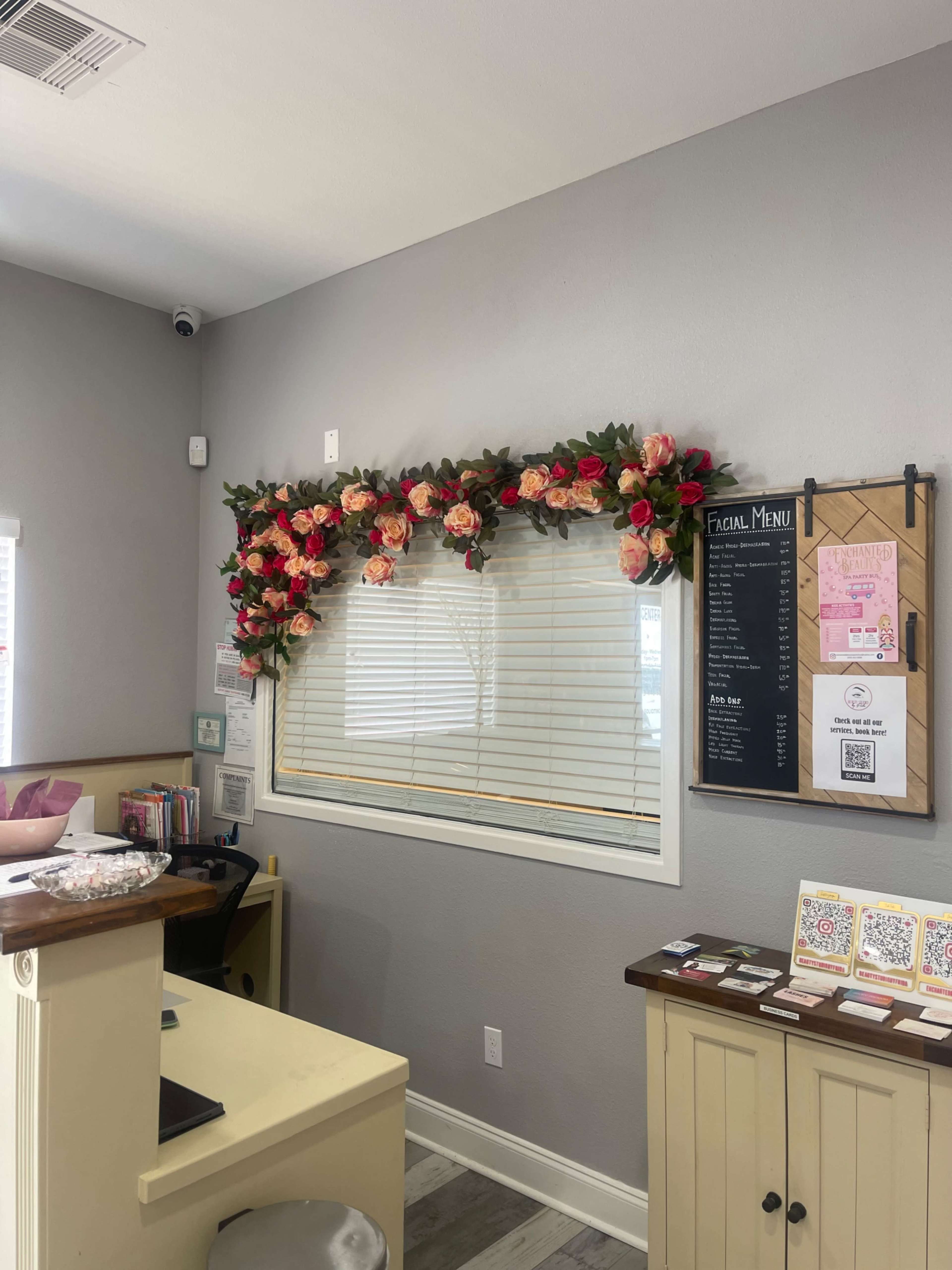 A decorative floral arrangement is mounted above a window in a reception area featuring a menu board and various printed materials.