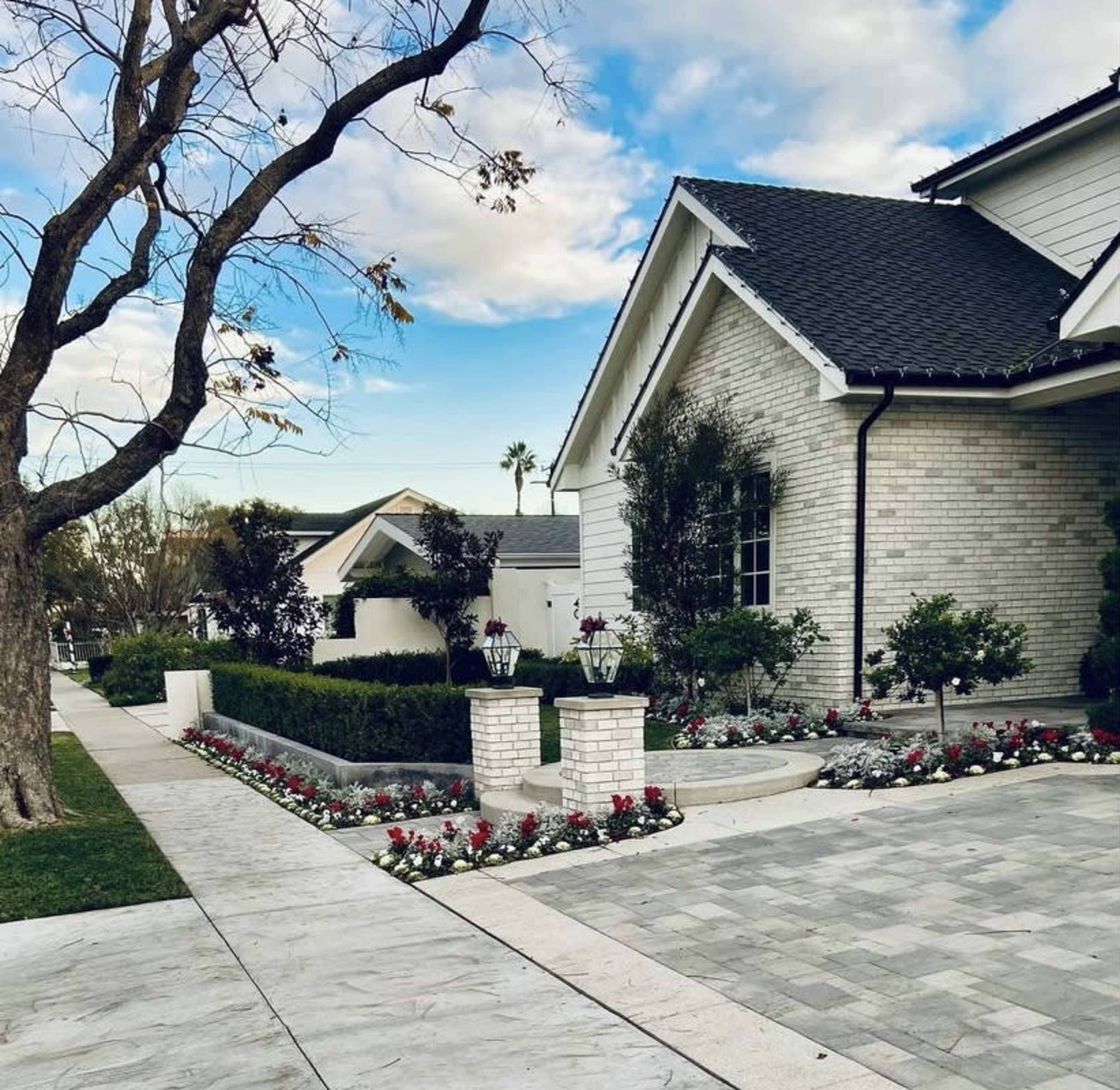 A well-maintained house features a brick exterior, neatly landscaped front yard, and a stone pathway lined with flowers.
