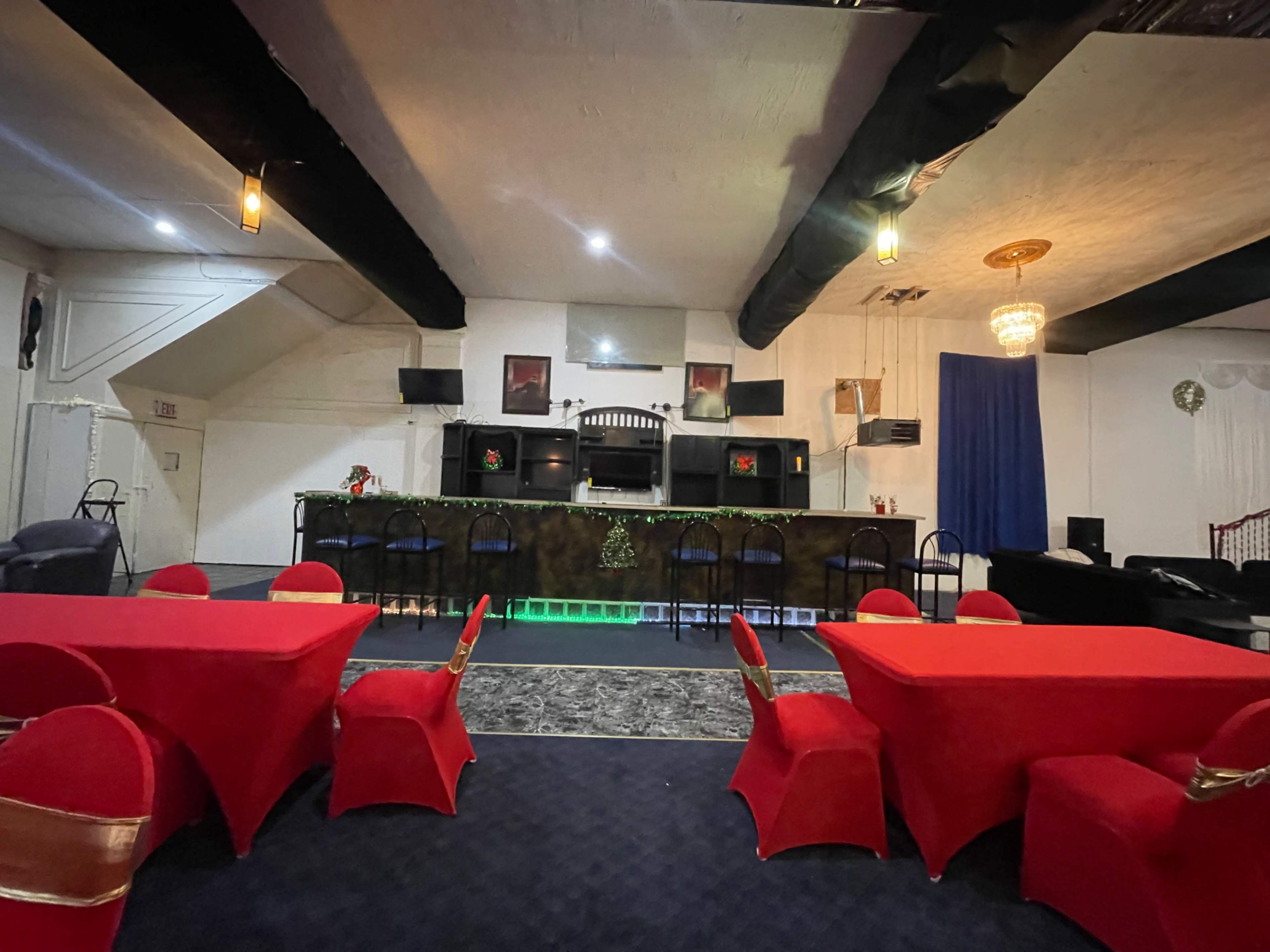 The interior features a bar area with a green lit counter, surrounded by red tables and chairs, under softly glowing lights.