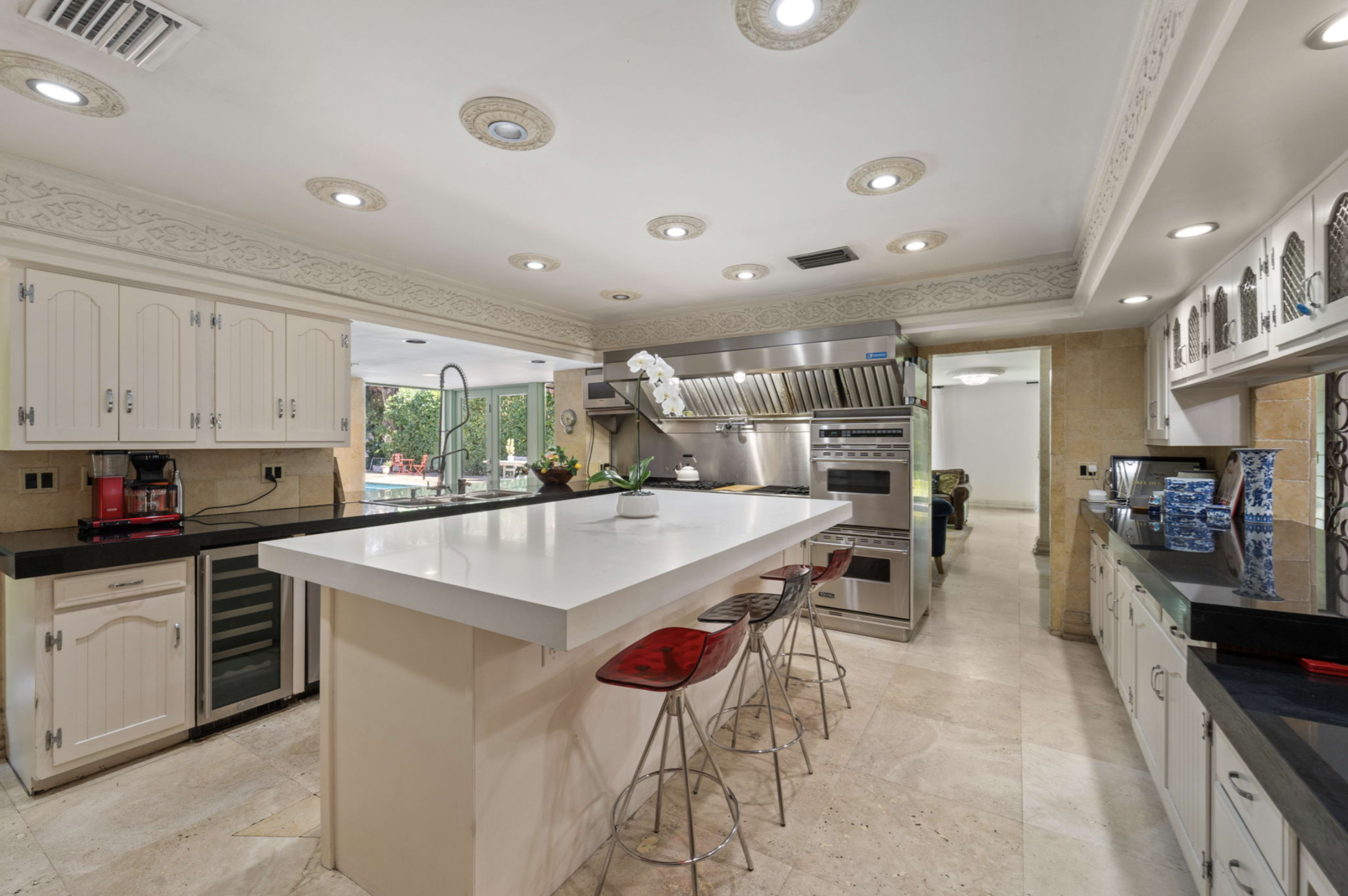 The image shows a modern kitchen with a large island, stainless steel appliances, and cream-colored cabinetry.
