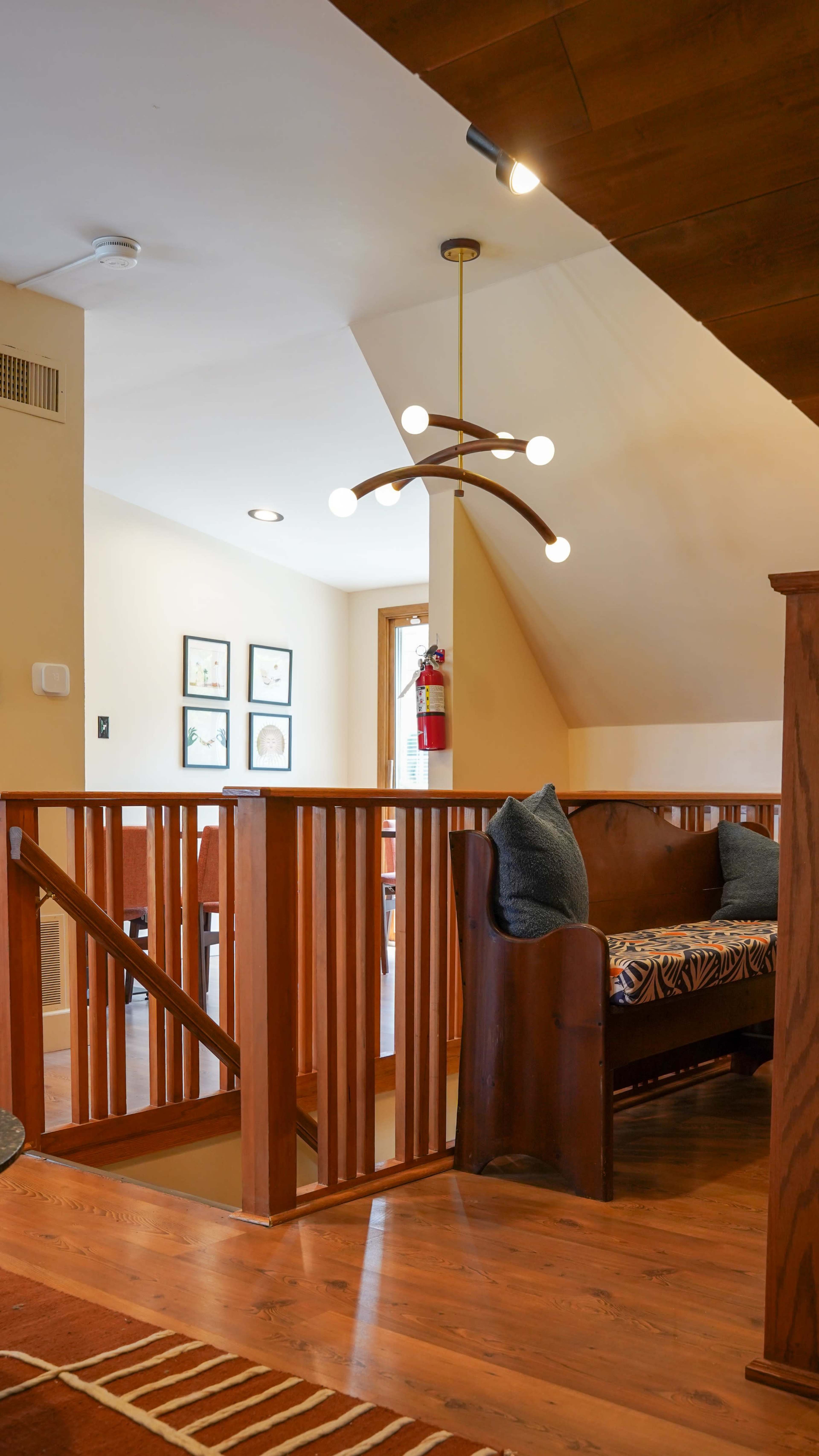 The scene features a wooden railing and a modern light fixture in a well-lit, open interior space.