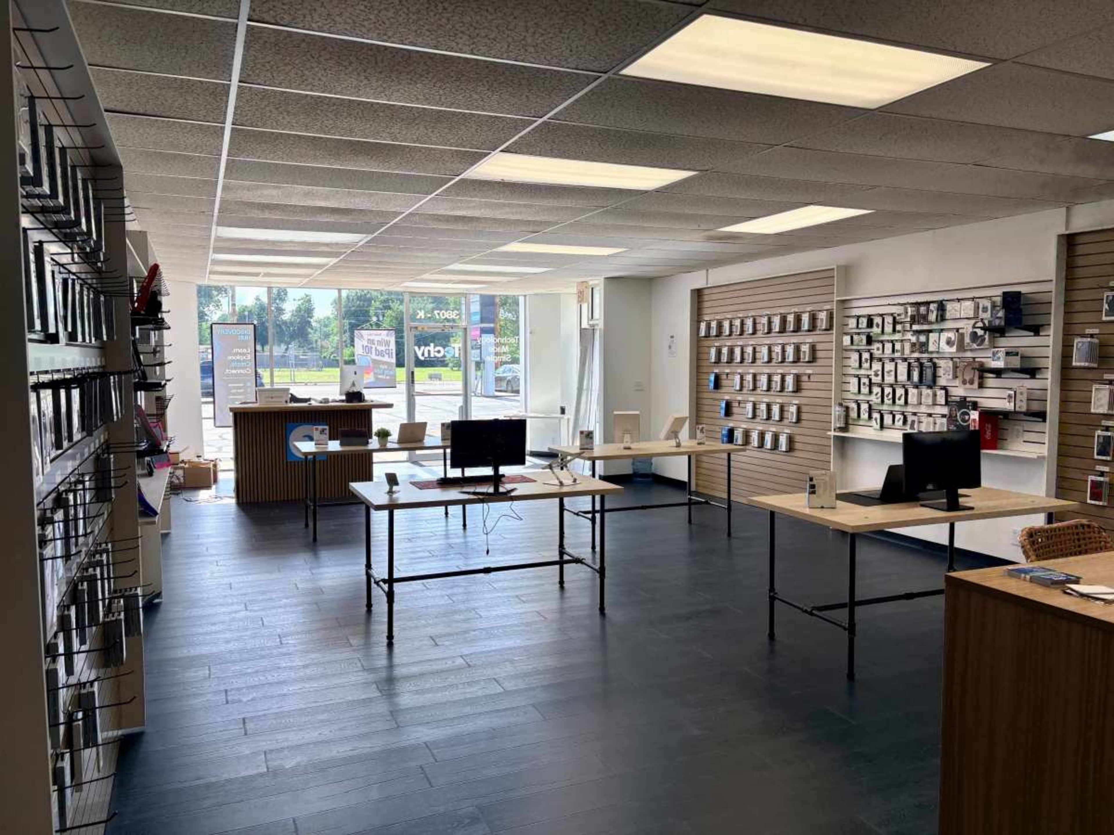 The image shows a retail store interior with display shelves on both sides, tables in the center, and windows facing the street.