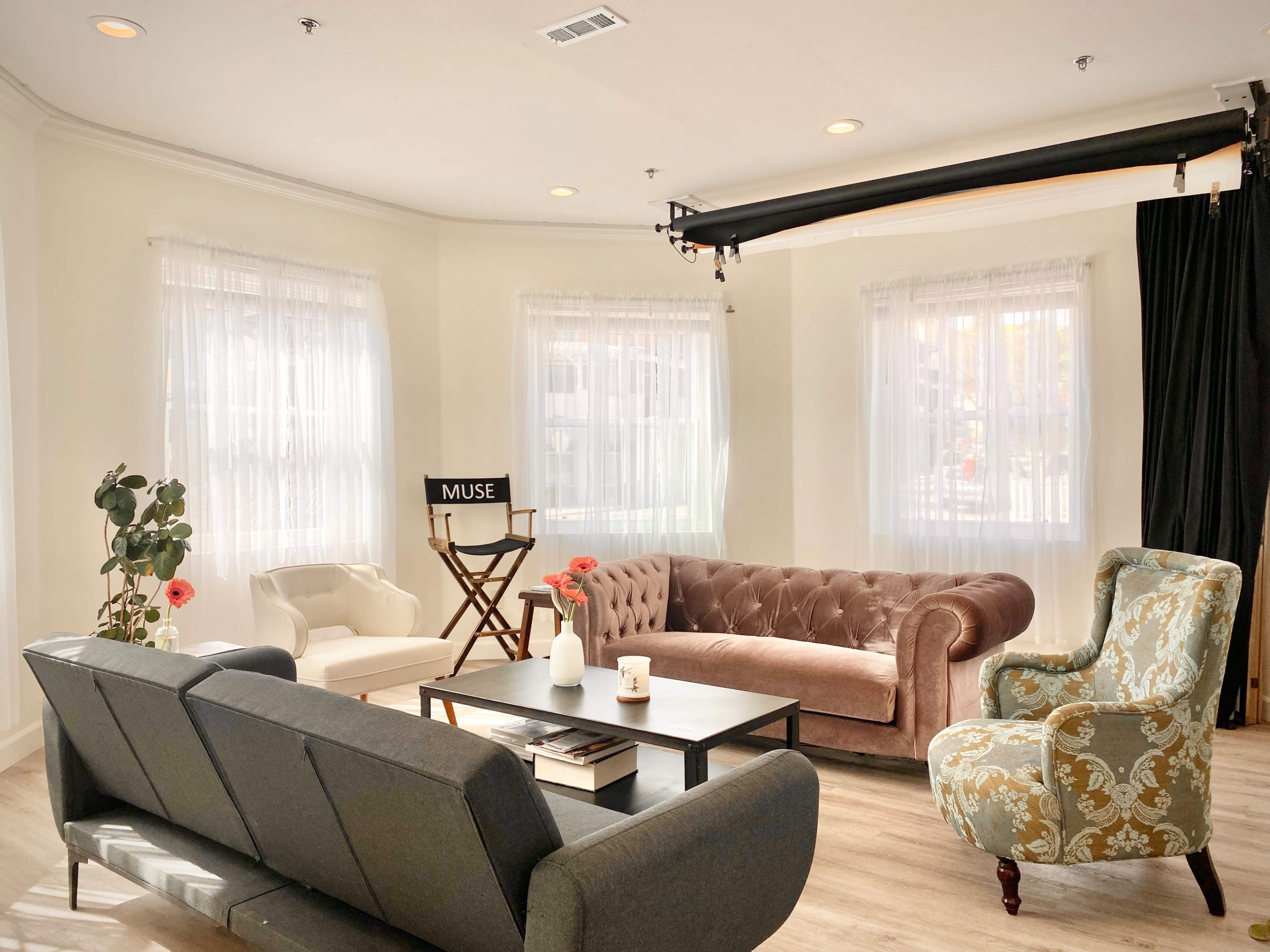 A well-lit room featuring various seating options, including a velvet sofa, an armchair with a floral pattern, and a contemporary couch, arranged around a coffee table.