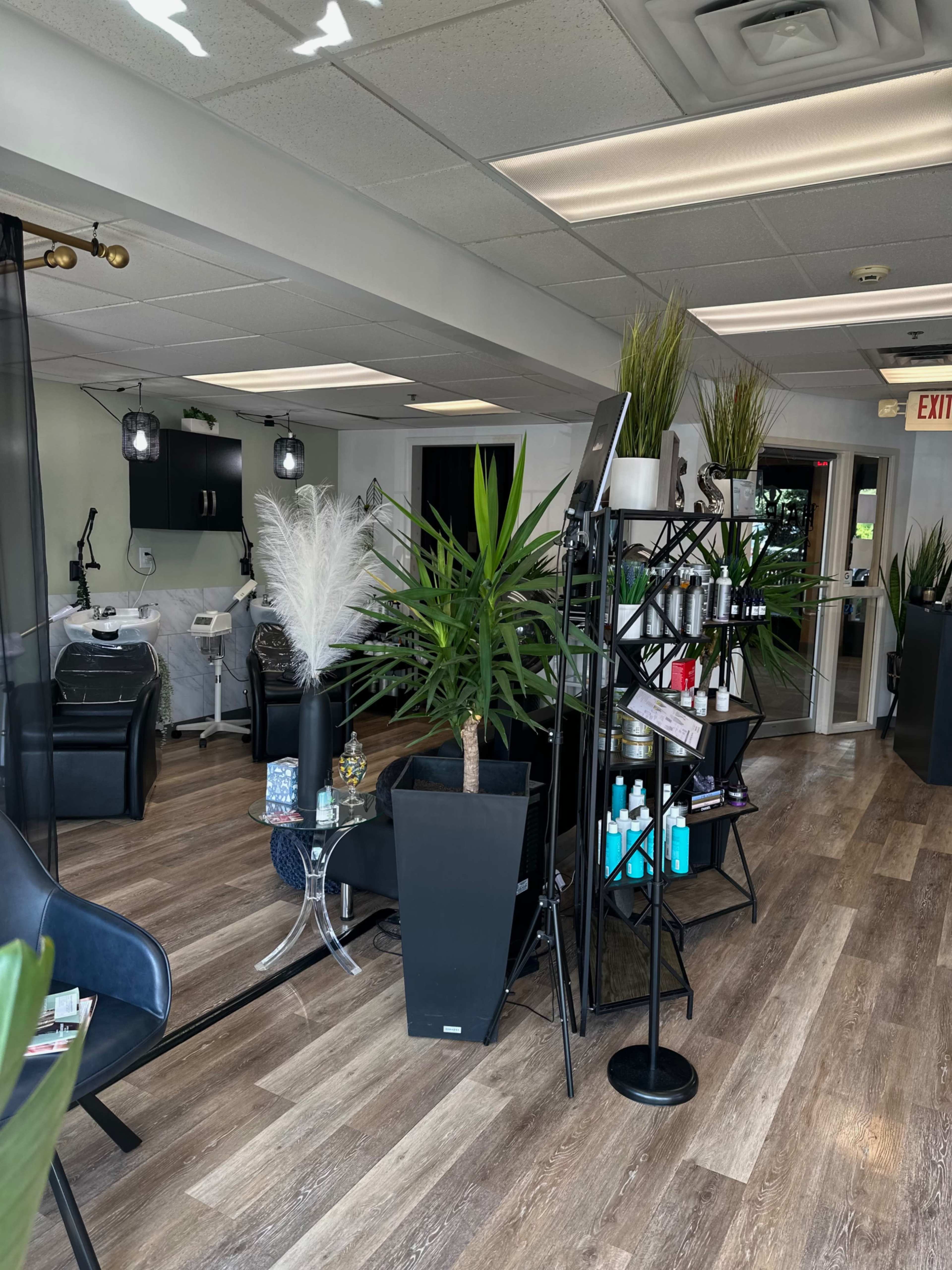 The interior of a modern salon with a combination of workstations, plants, and product displays on sleek shelving.