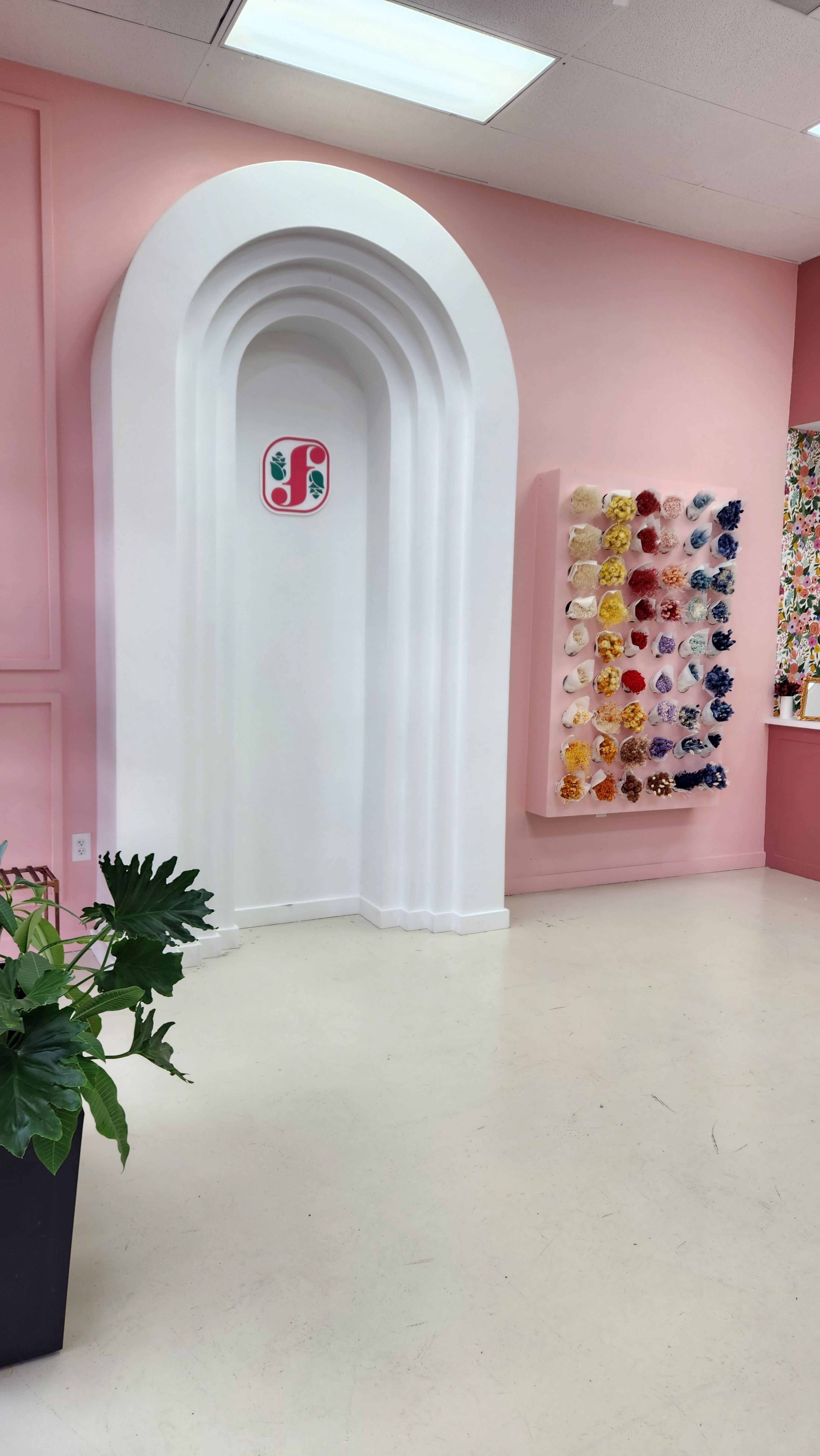 A bright pink room featuring an archway beside a colorful wall display of hair accessories.