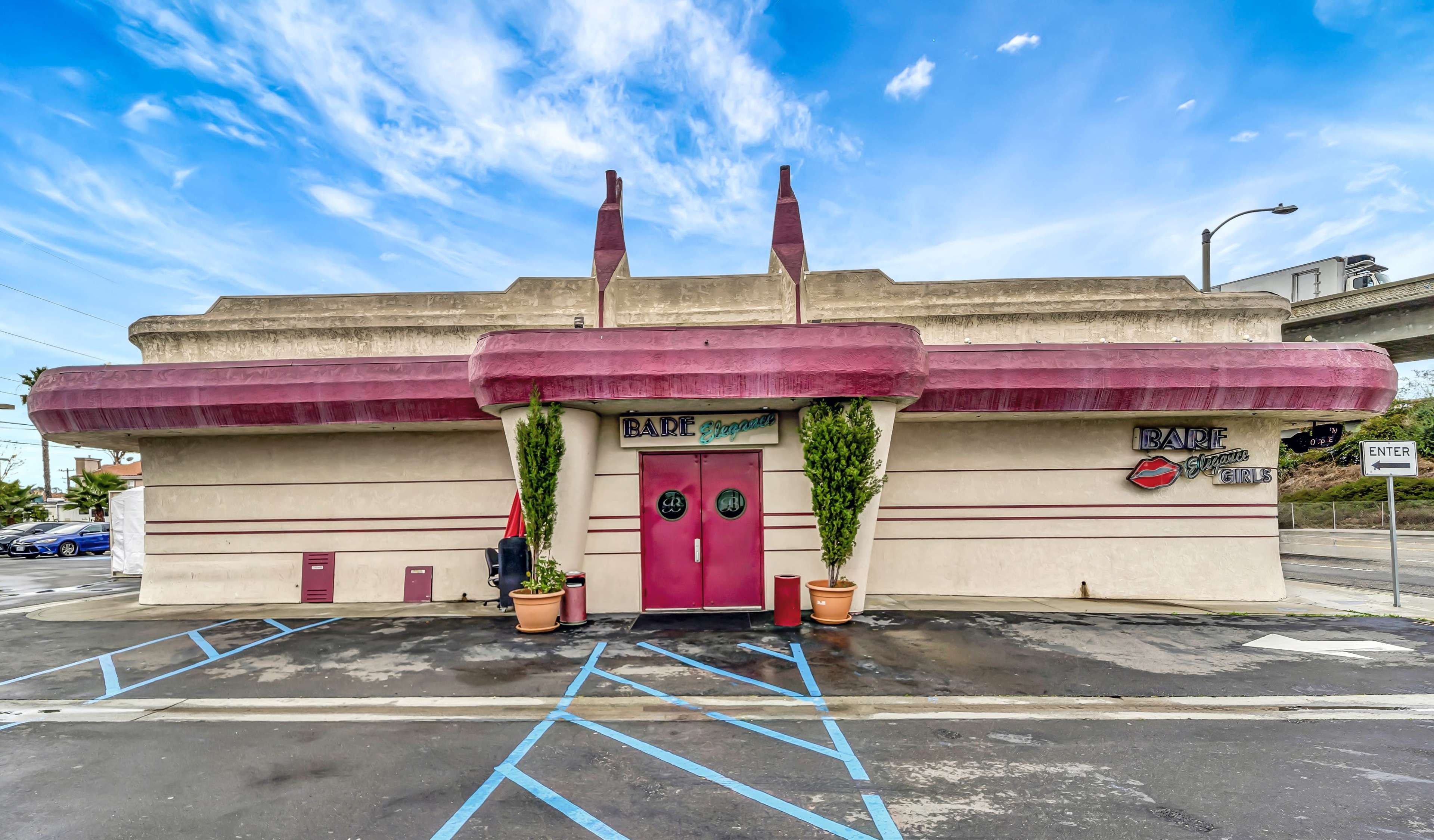 The image shows a unique building with a distinctive architectural style featuring a pink facade and decorative elements on the roof.