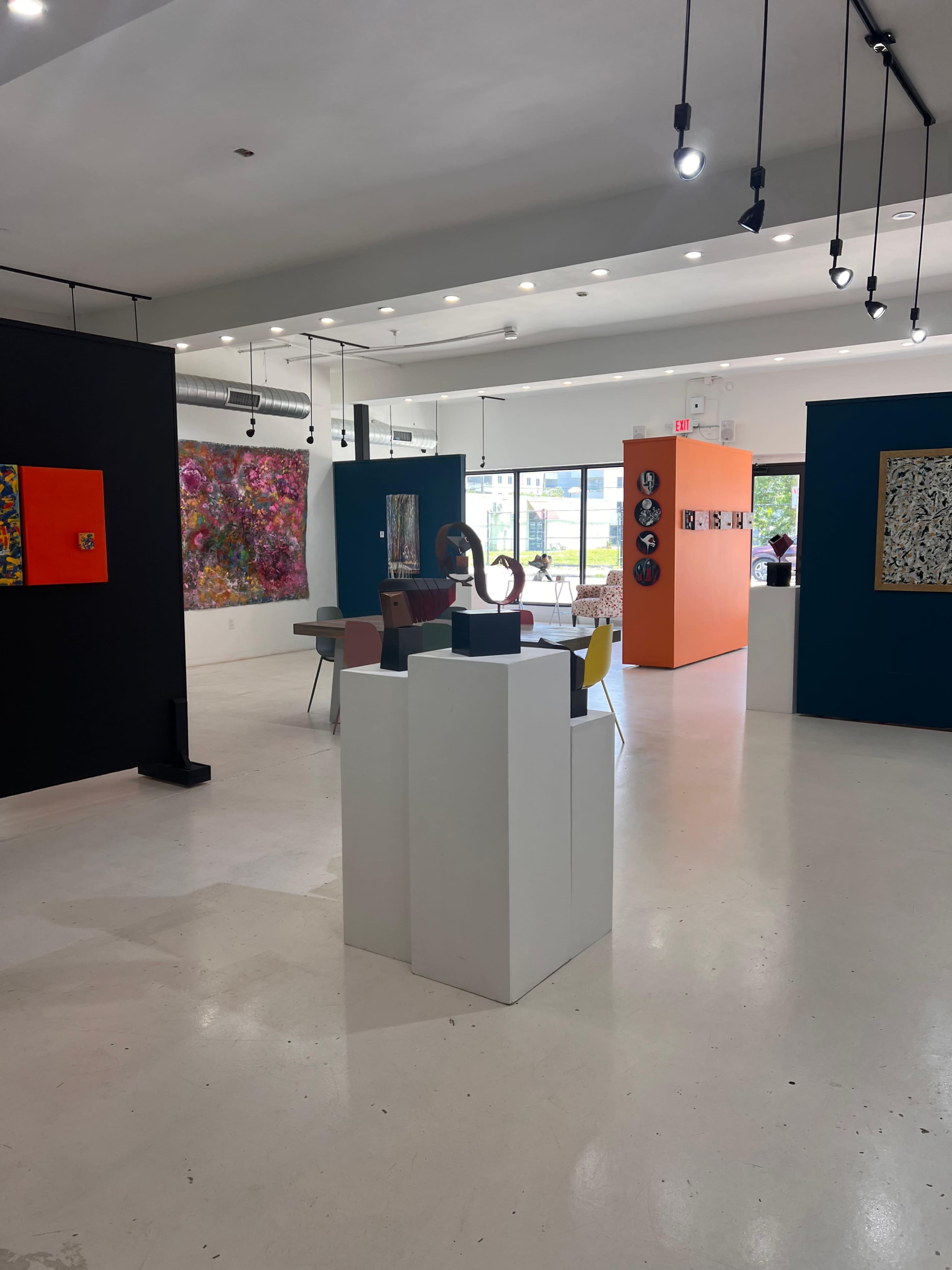 The image shows an art gallery with colorful wall displays and sculptures on pedestals.