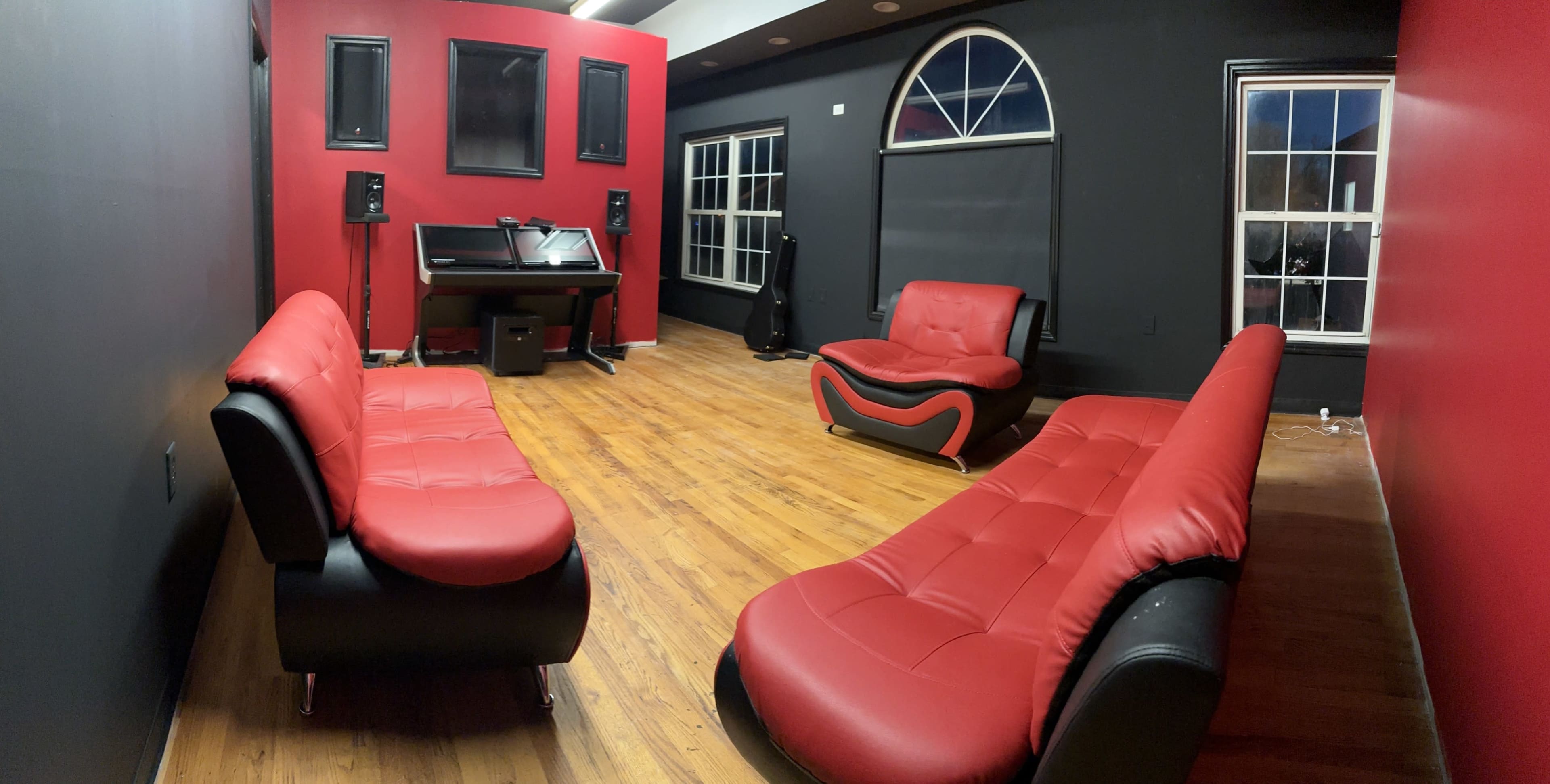 The image shows a modern room with red and black walls, featuring stylish red and black seating, a piano, and large windows.