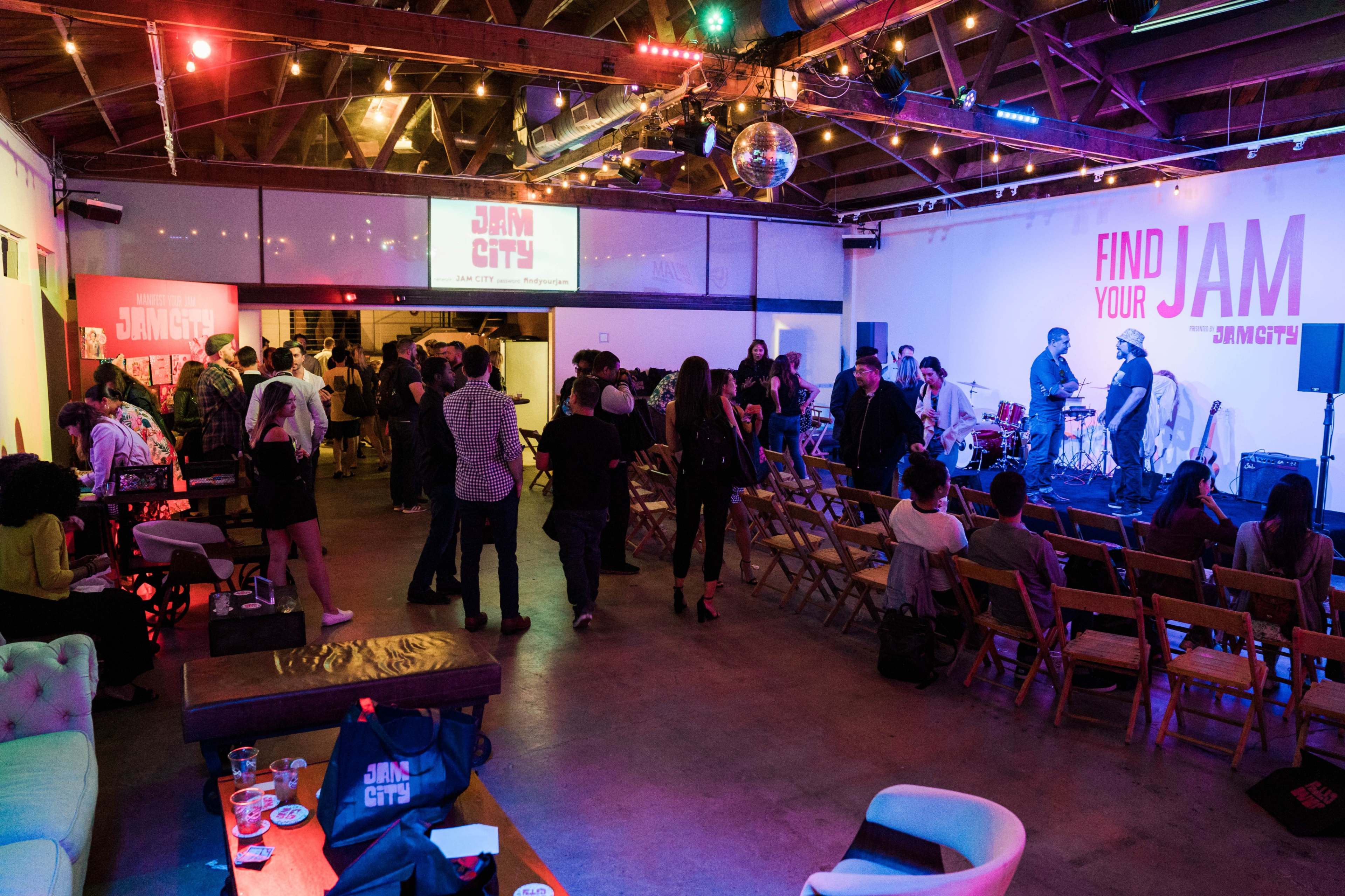 A lively event space features a crowd gathered around a stage with musicians, while colorful lights illuminate the room.