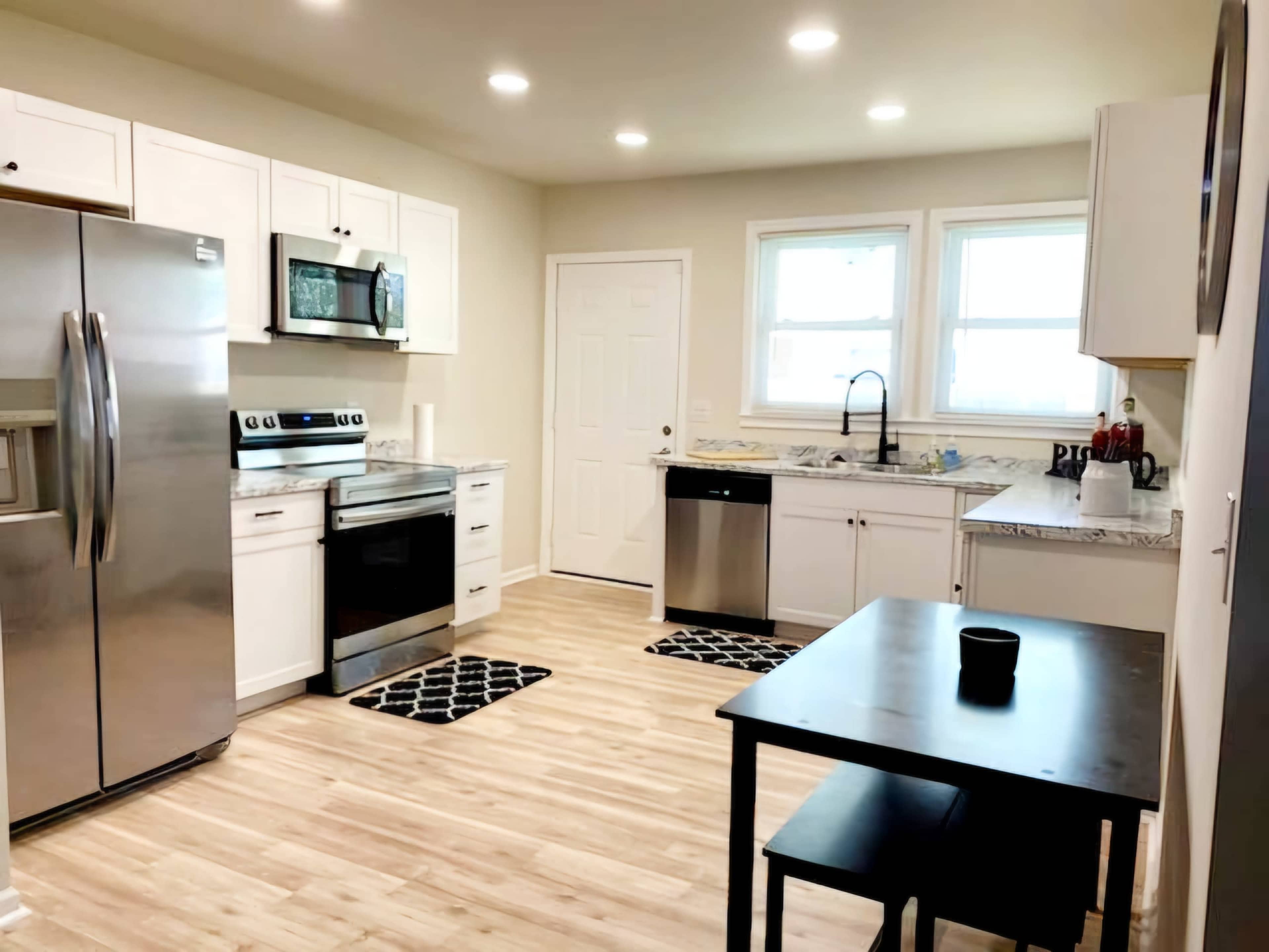 A modern kitchen featuring stainless steel appliances, white cabinetry, and a wooden floor.