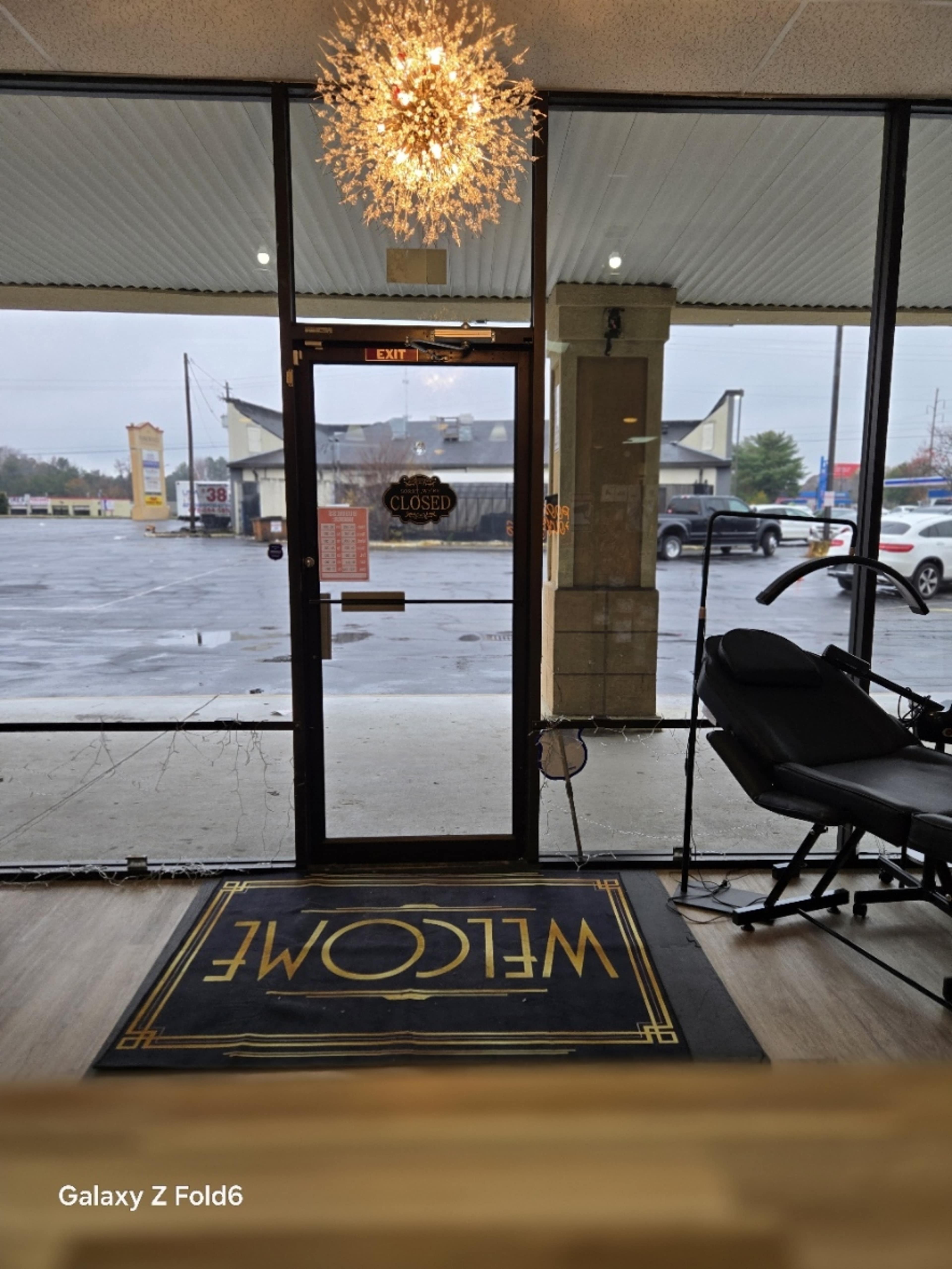 The image shows the entrance of a closed salon with a "Welcome" mat and a light fixture above the door.
