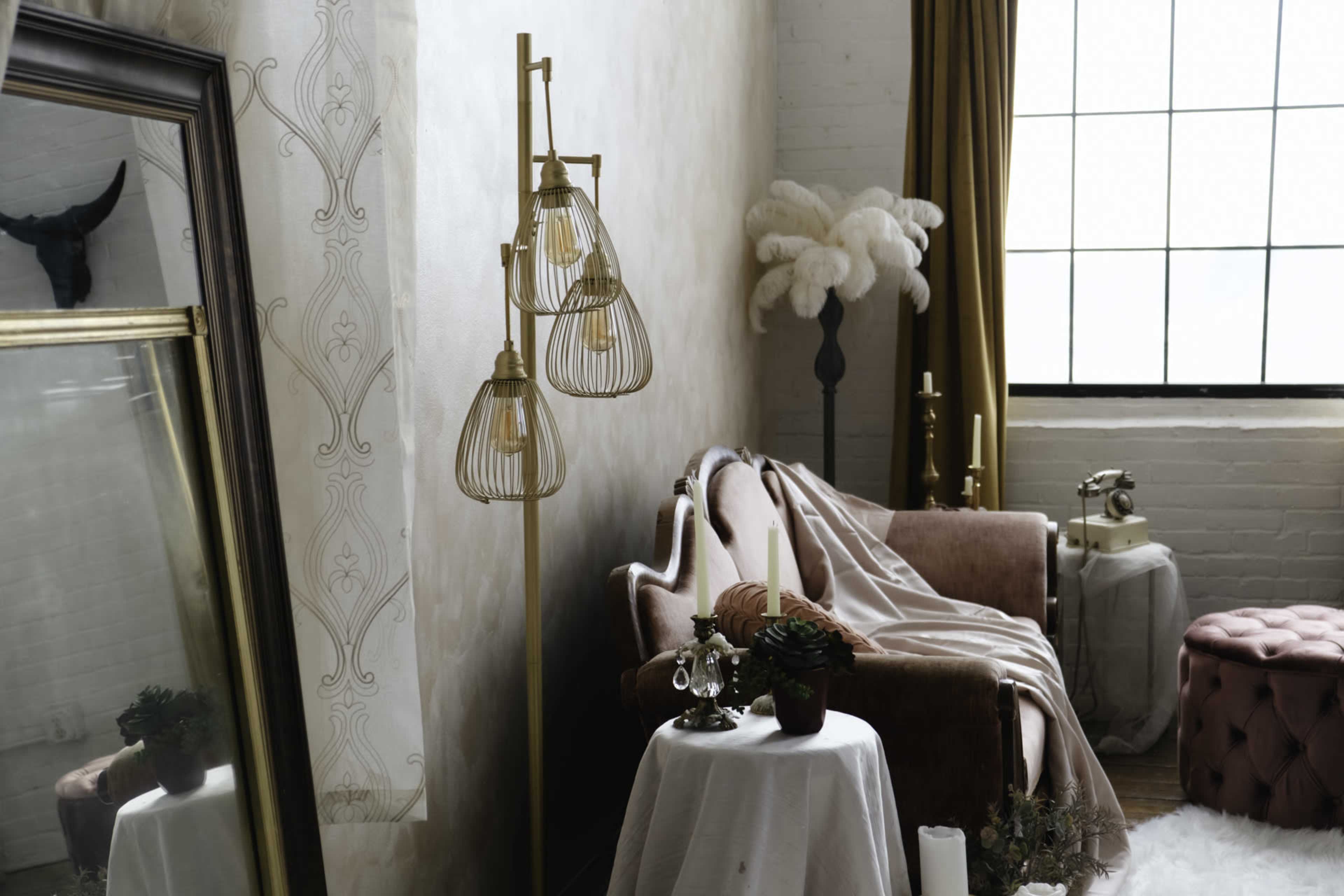 The image features a stylish interior scene, showcasing a plush pink sofa, decorative plants, a vintage mirror, and various lighting fixtures against a backdrop of large windows and soft textiles.