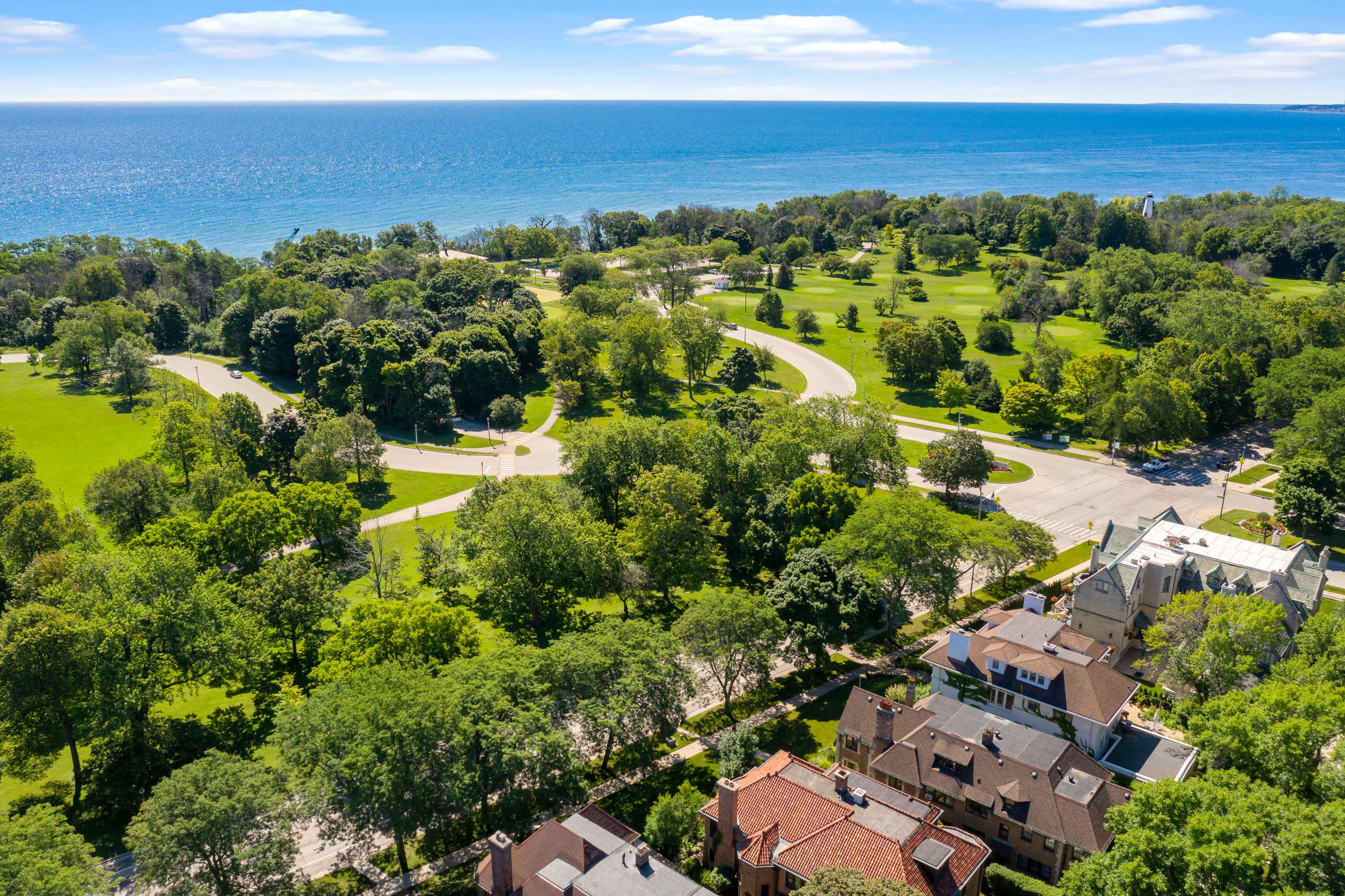 A scenic view of a park with winding paths and lush greenery adjacent to a waterfront.