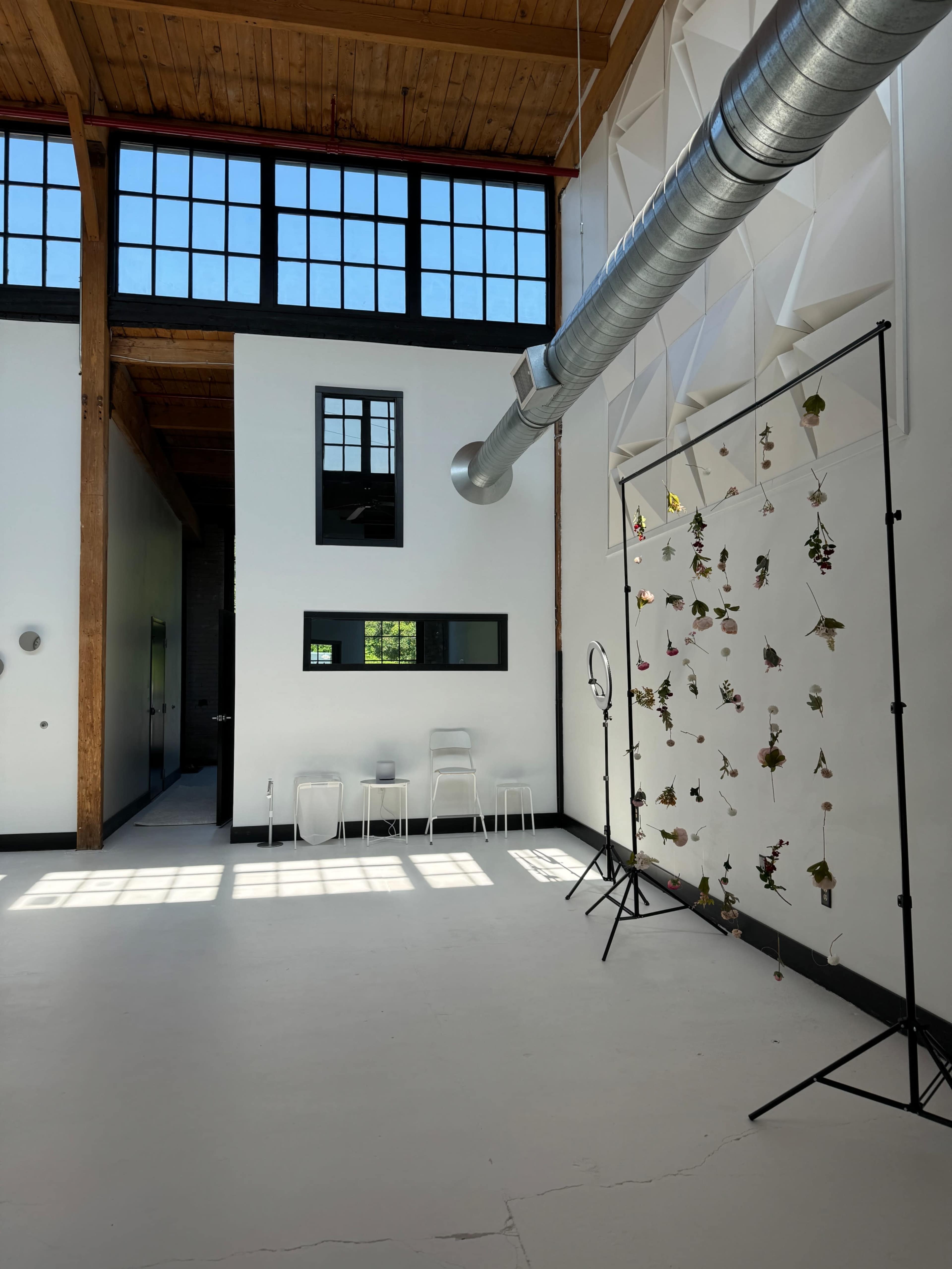 An expansive interior space with high ceilings, large windows, and a hanging display of plants.