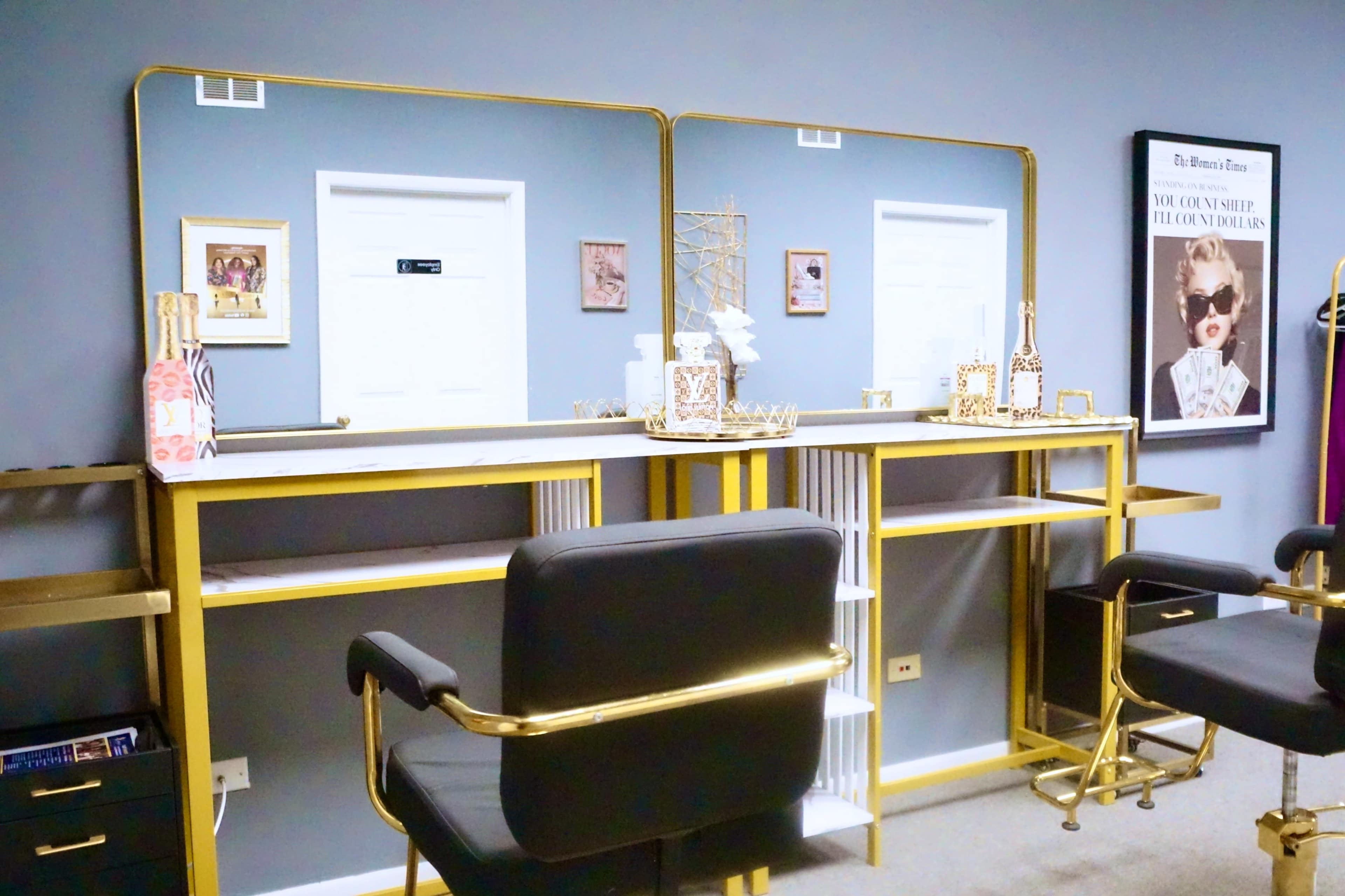 The image shows a beauty salon setup featuring two mirrored stations with gold accents, black chairs, and decorative items on the counters.