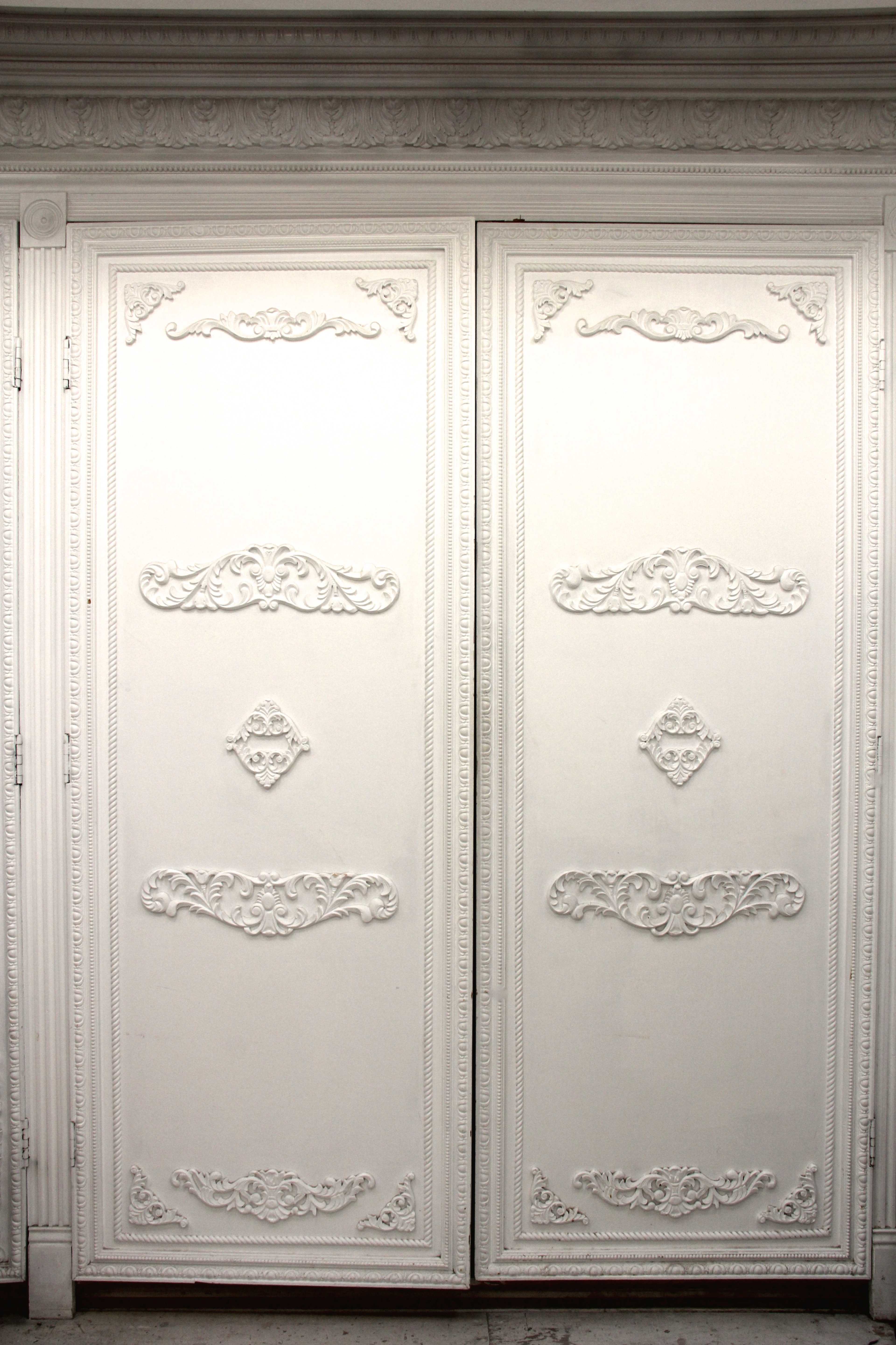A pair of ornate white double doors with decorative moldings and carvings.