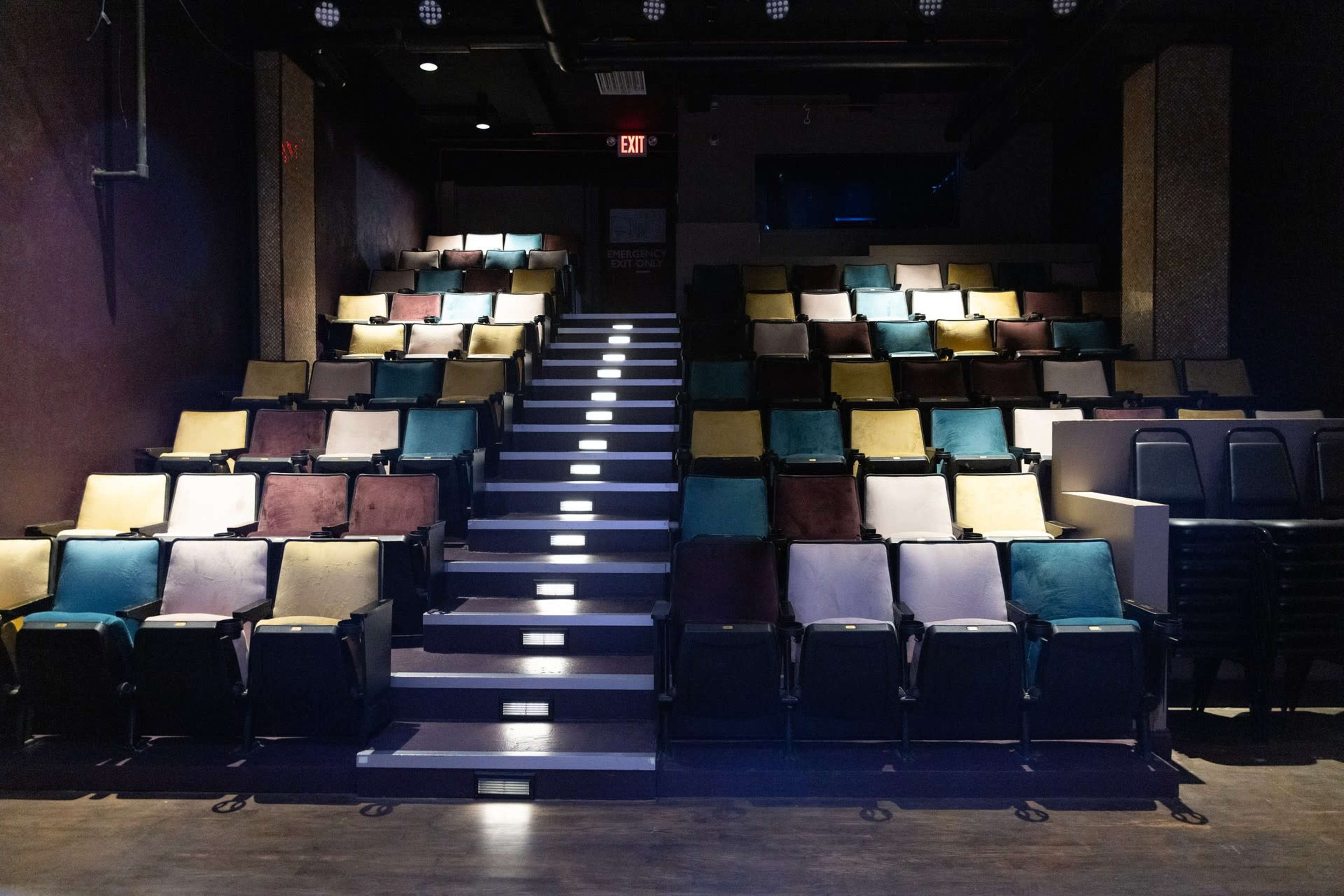 A seating area in a theater with rows of multicolored chairs arranged in ascending order.