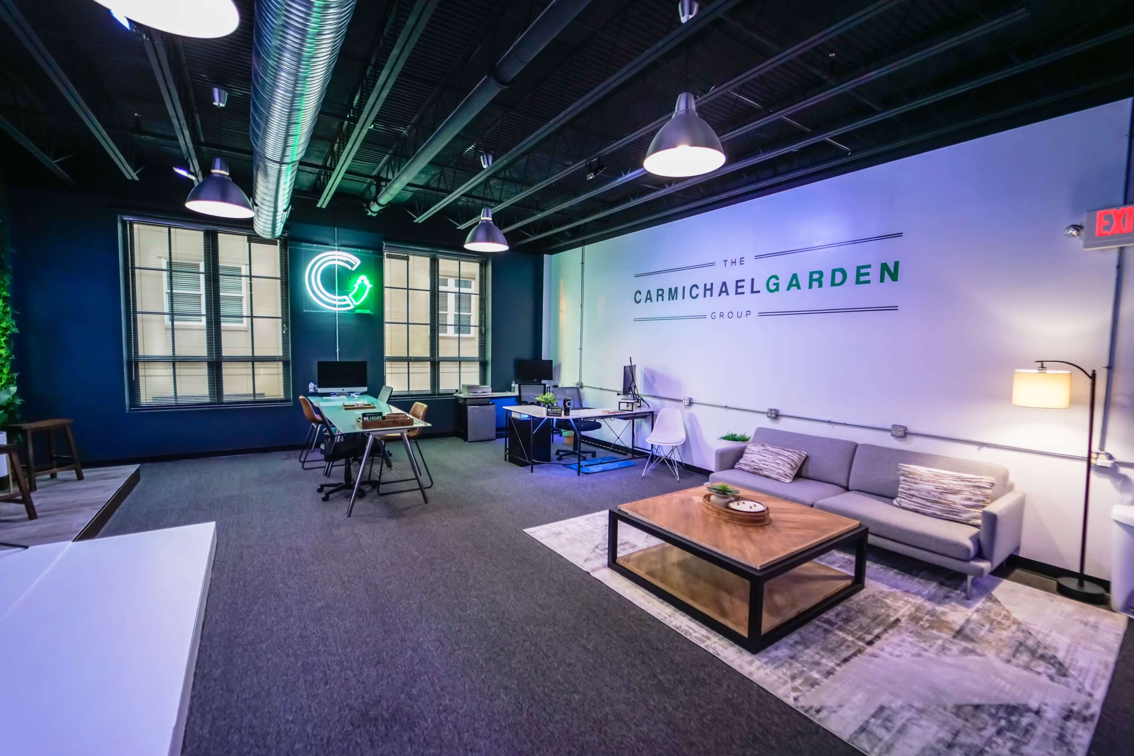 A modern office space with a seating area, workstations, and a large company logo on the wall.