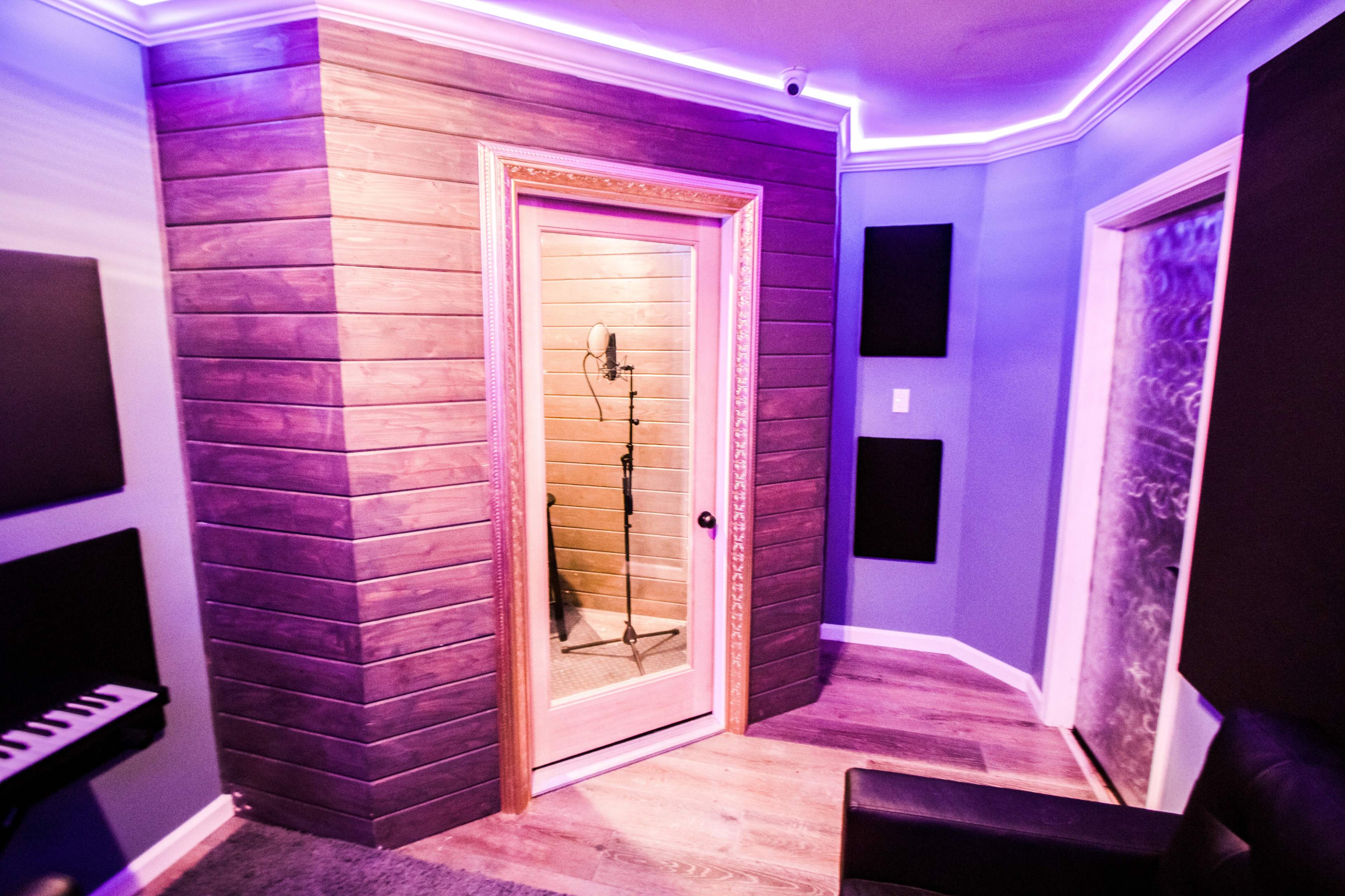 A soundproof recording booth with a microphone inside, surrounded by soundproof panels and dim lighting.
