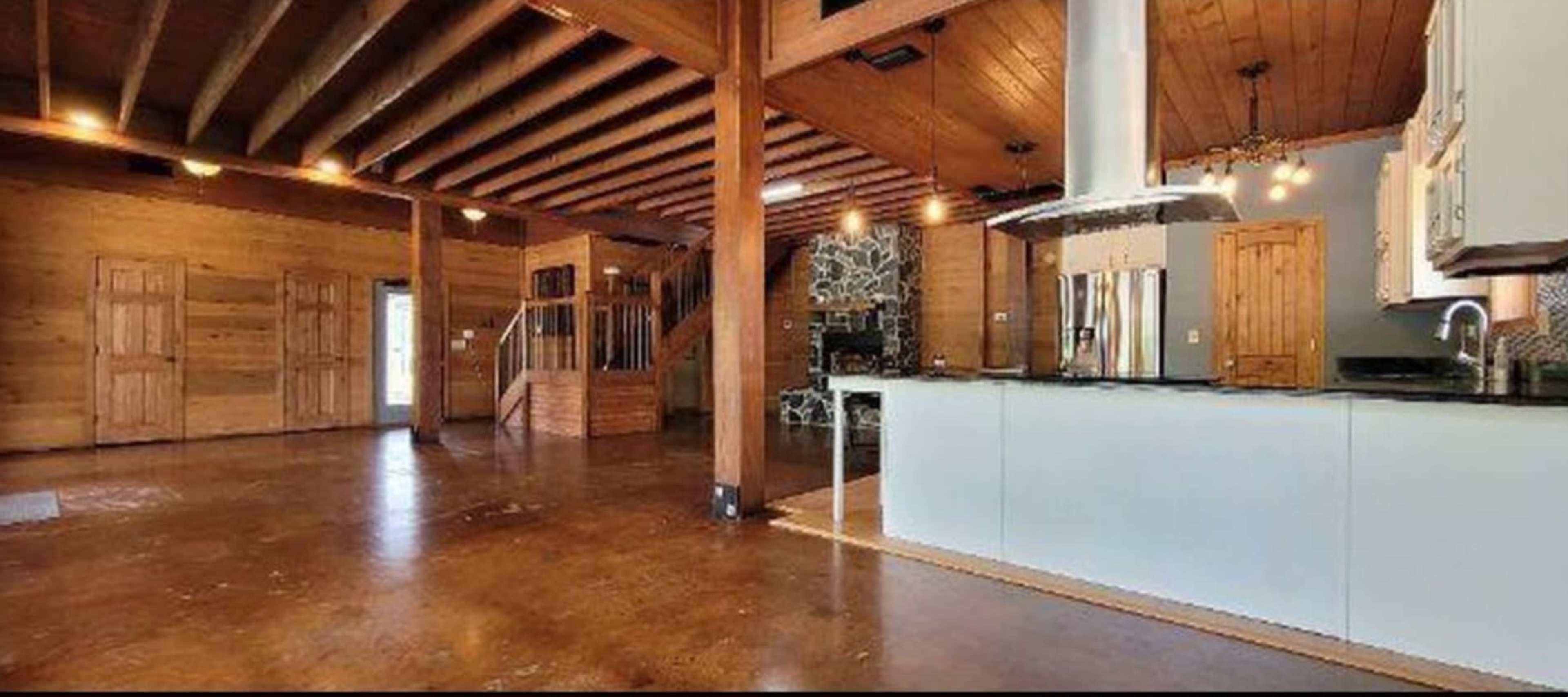 The spacious interior features wooden beams, a stone fireplace, and a modern kitchen with an island.