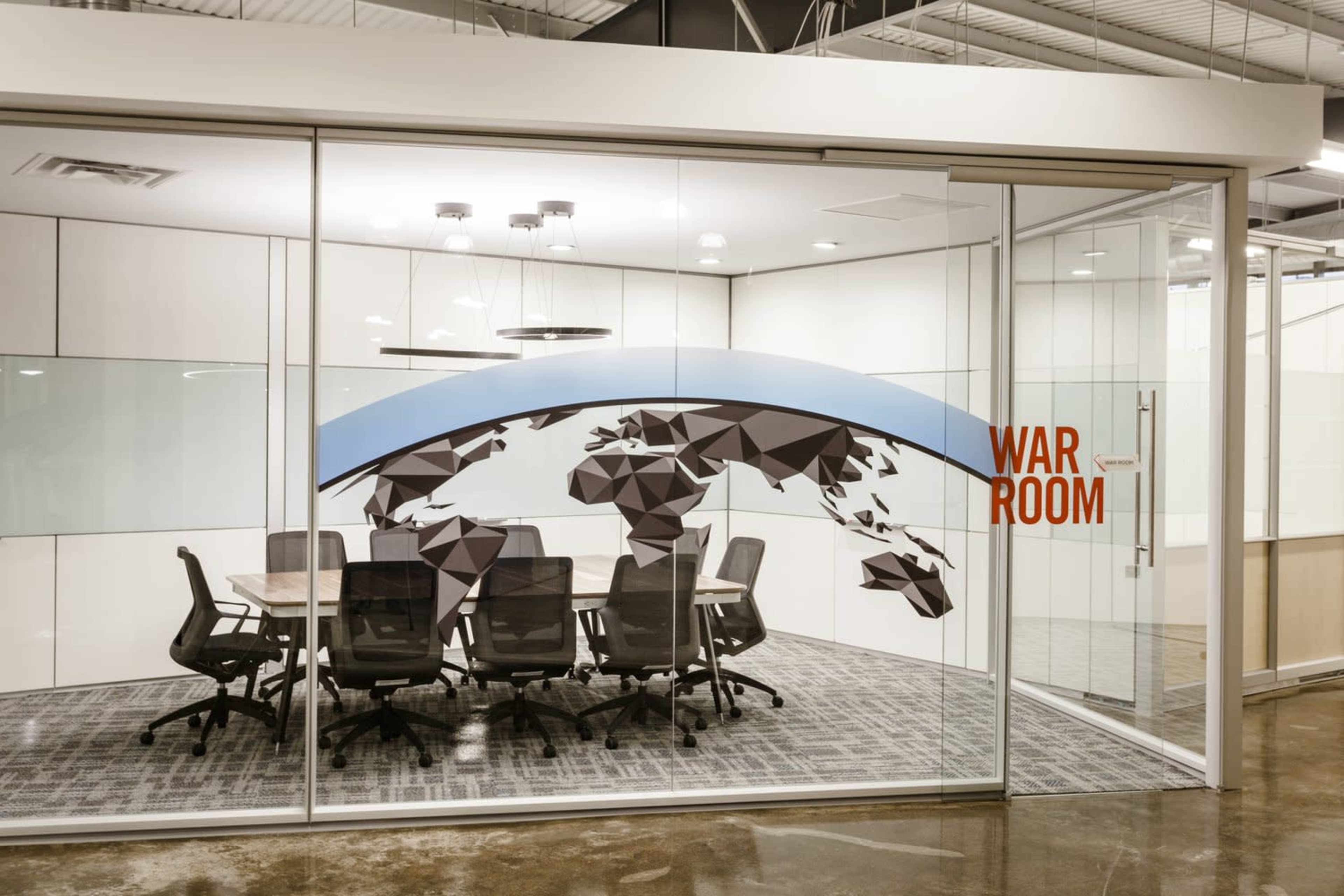 A modern conference room with a glass wall featuring a world map design and the words "WAR ROOM" prominently displayed.