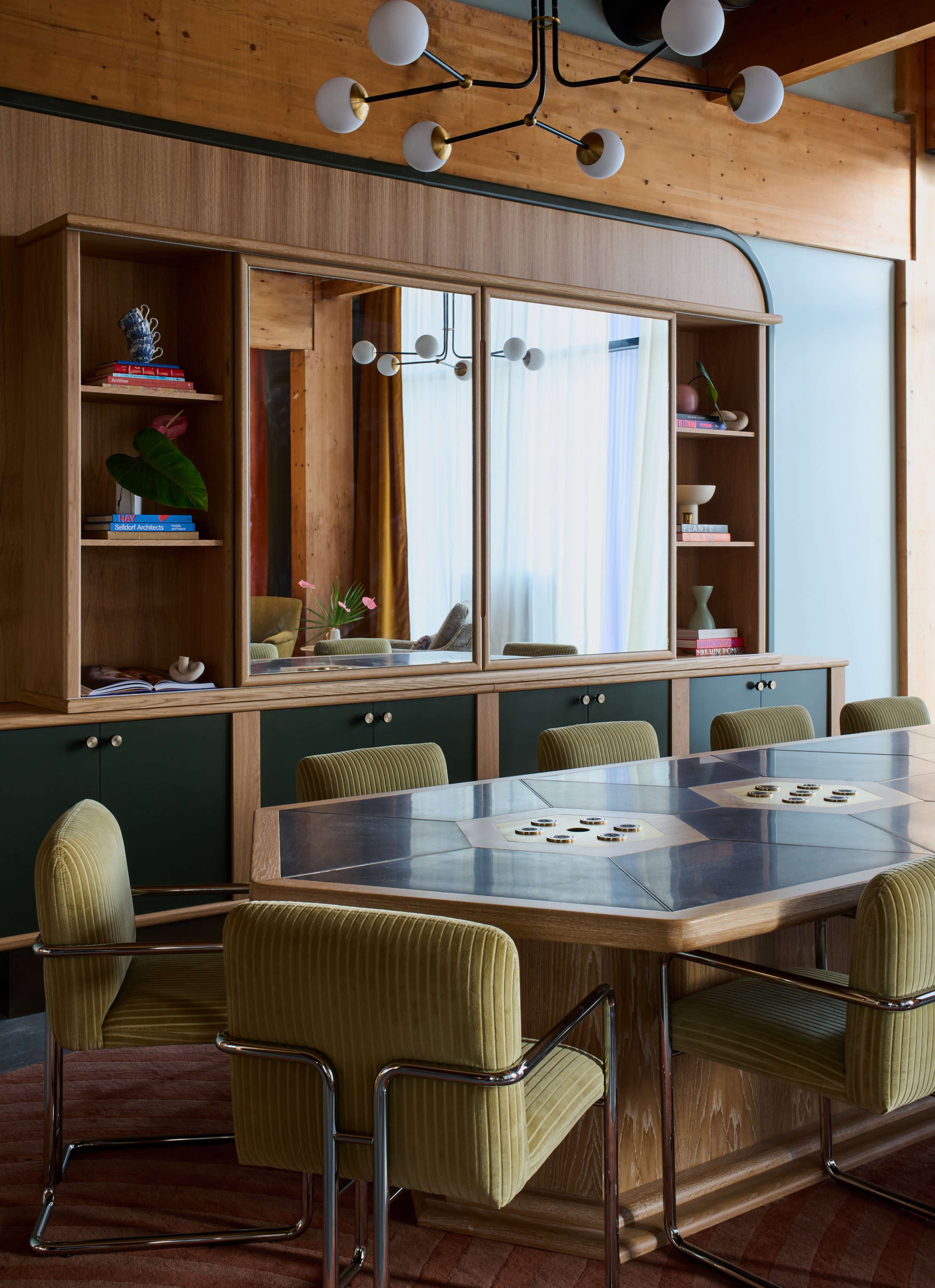 A modern dining area features a wooden table surrounded by upholstered chairs, with a glass-fronted cabinet displaying decorative items in the background.