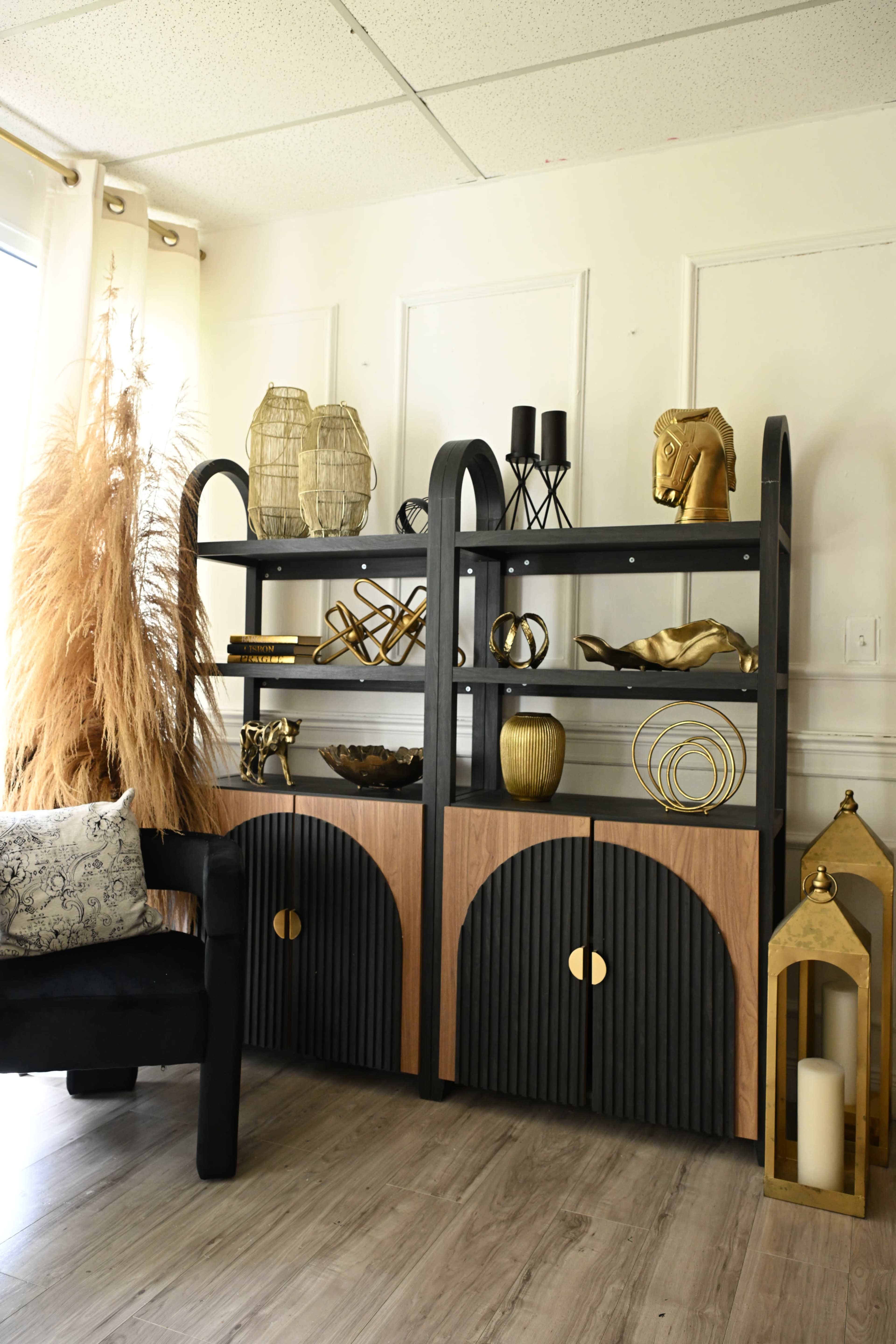 The image shows a modern shelving unit with black and wooden elements, displaying various decorative items and plants in a well-lit room.