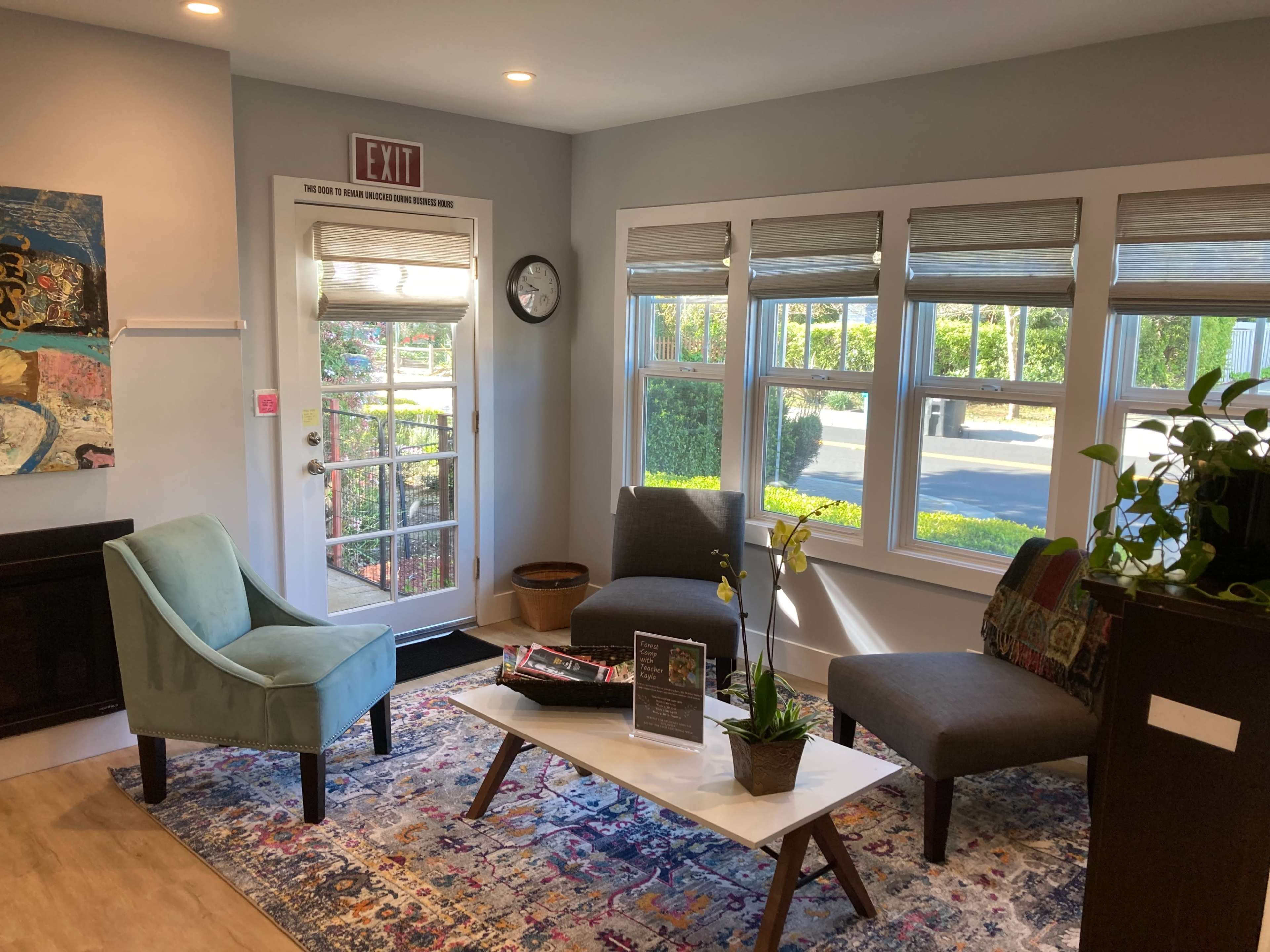 A bright waiting area with two chairs, a coffee table, and large windows letting in natural light.