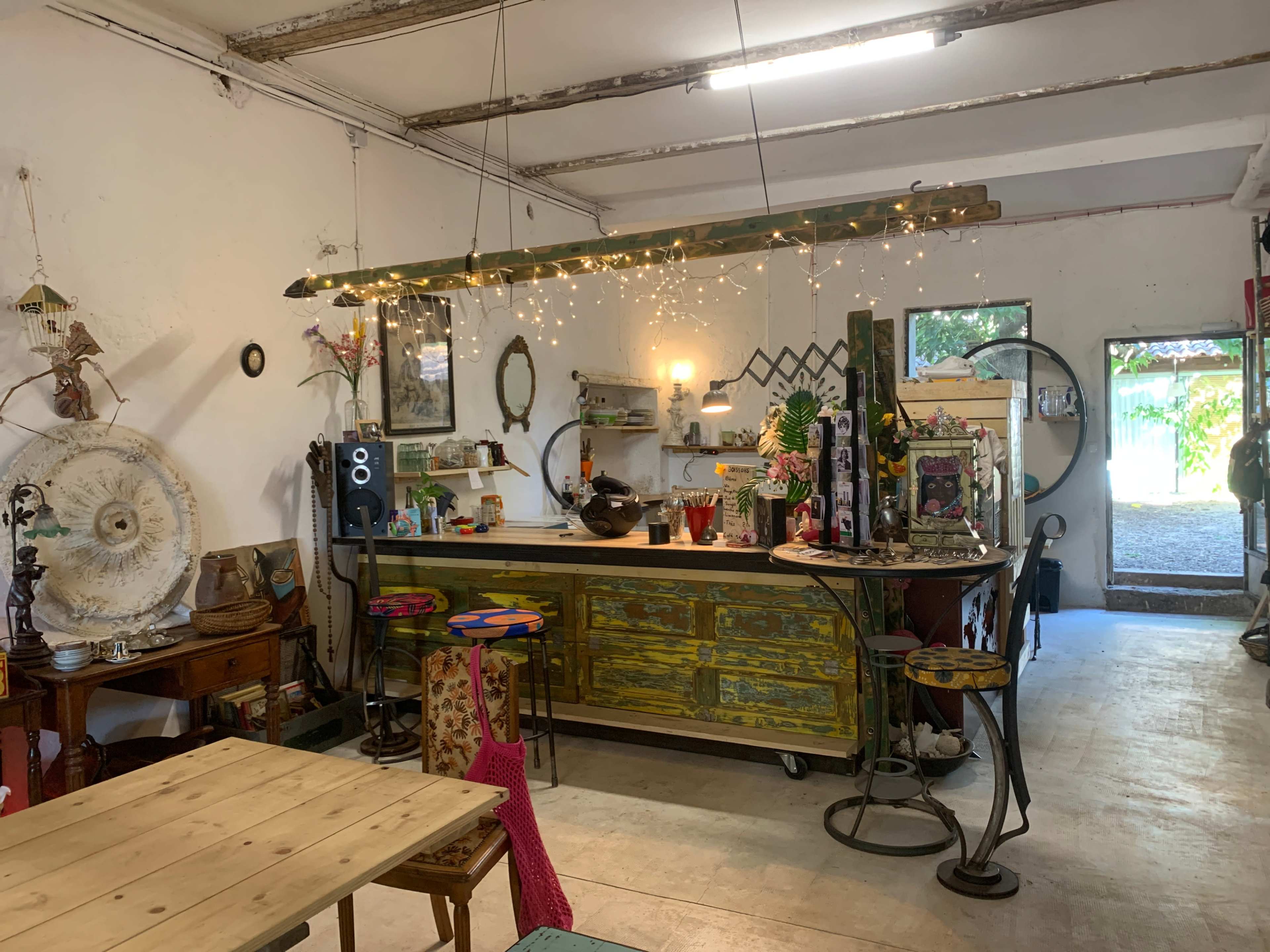 The image shows a cozy, eclectic kitchen space with a long wooden counter, decorative items on shelves, and warm lighting.