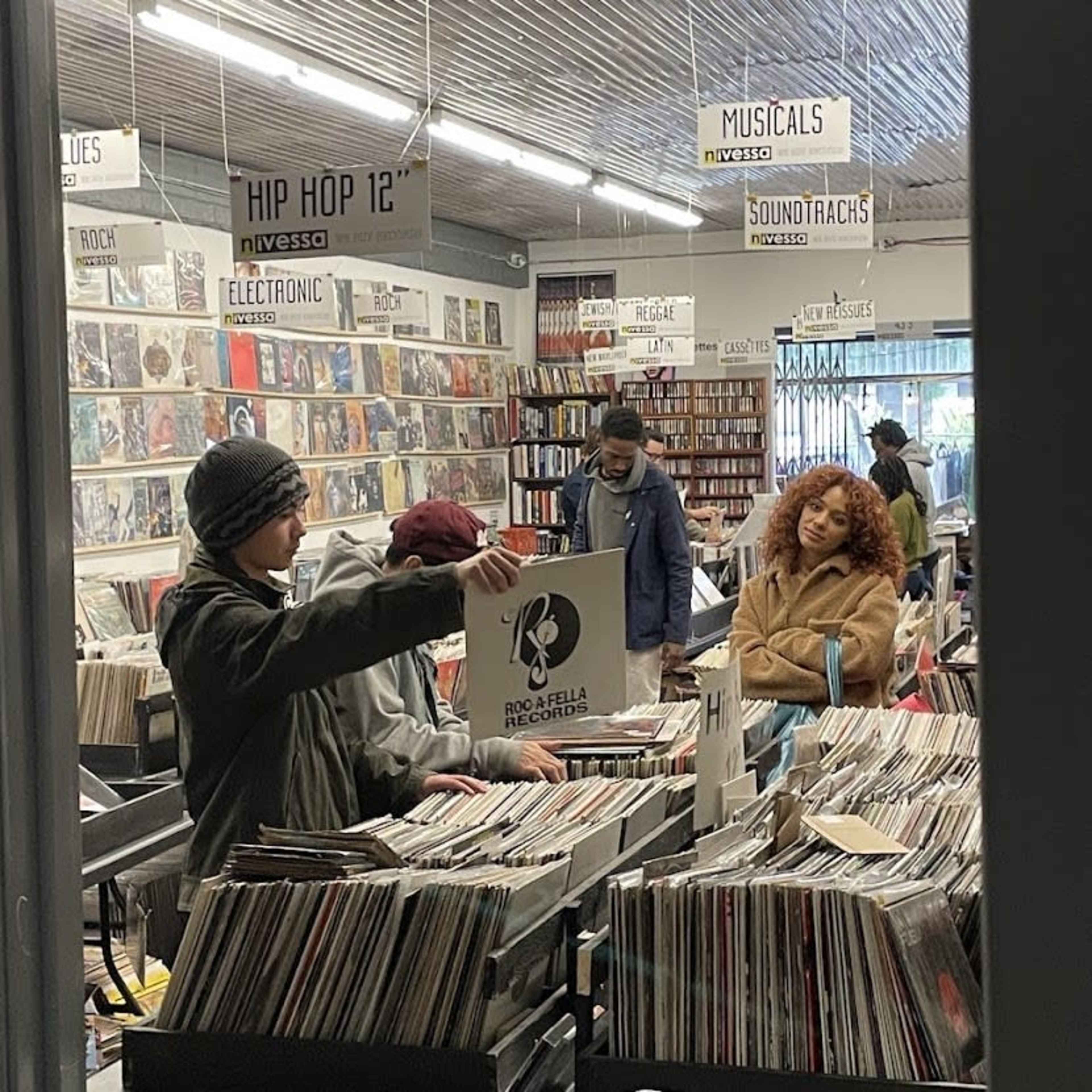 A group of people browse through rows of vinyl records in a music store.