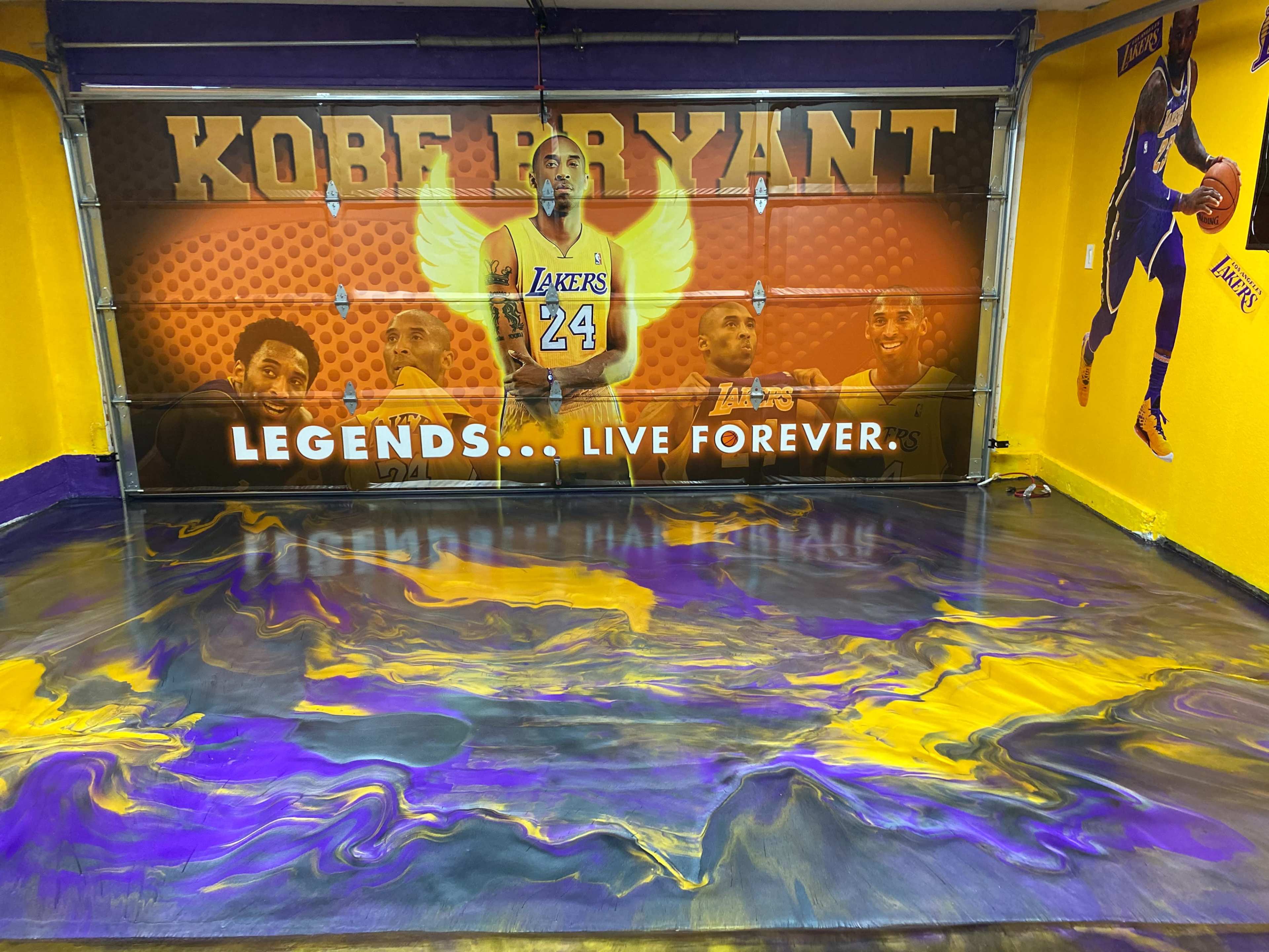 A garage with a mural of Kobe Bryant and a floor featuring a purple and gold swirl pattern.