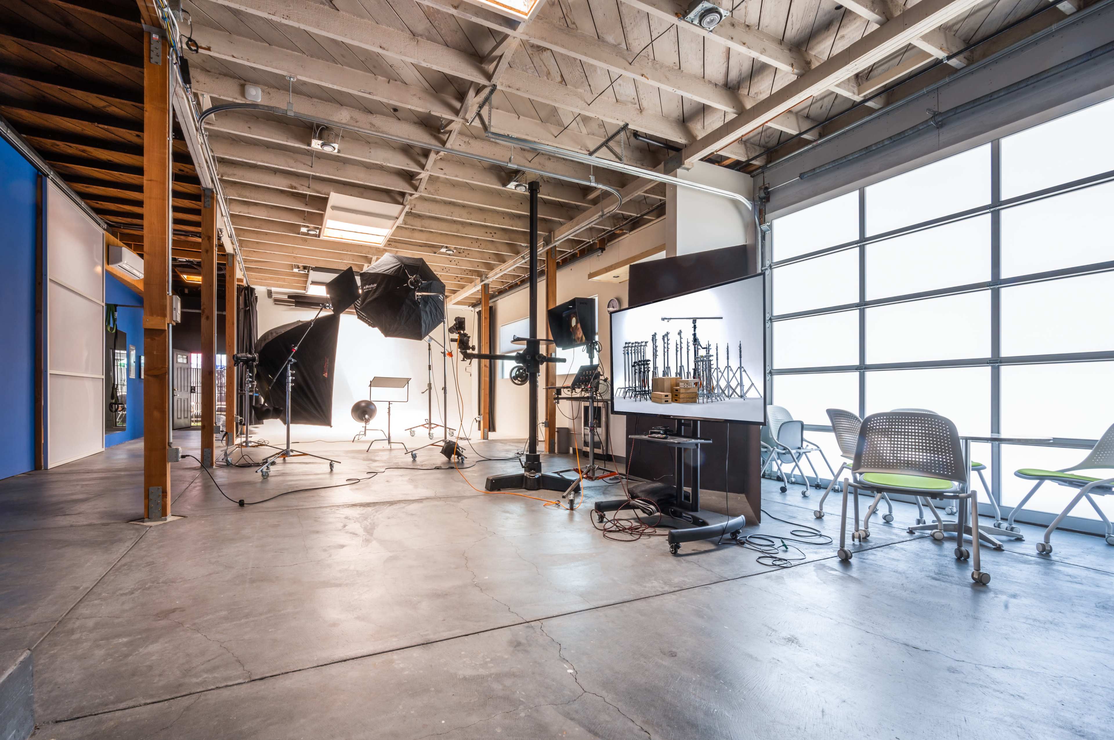 A spacious photography studio with various lighting equipment, a backdrop, and seating areas.