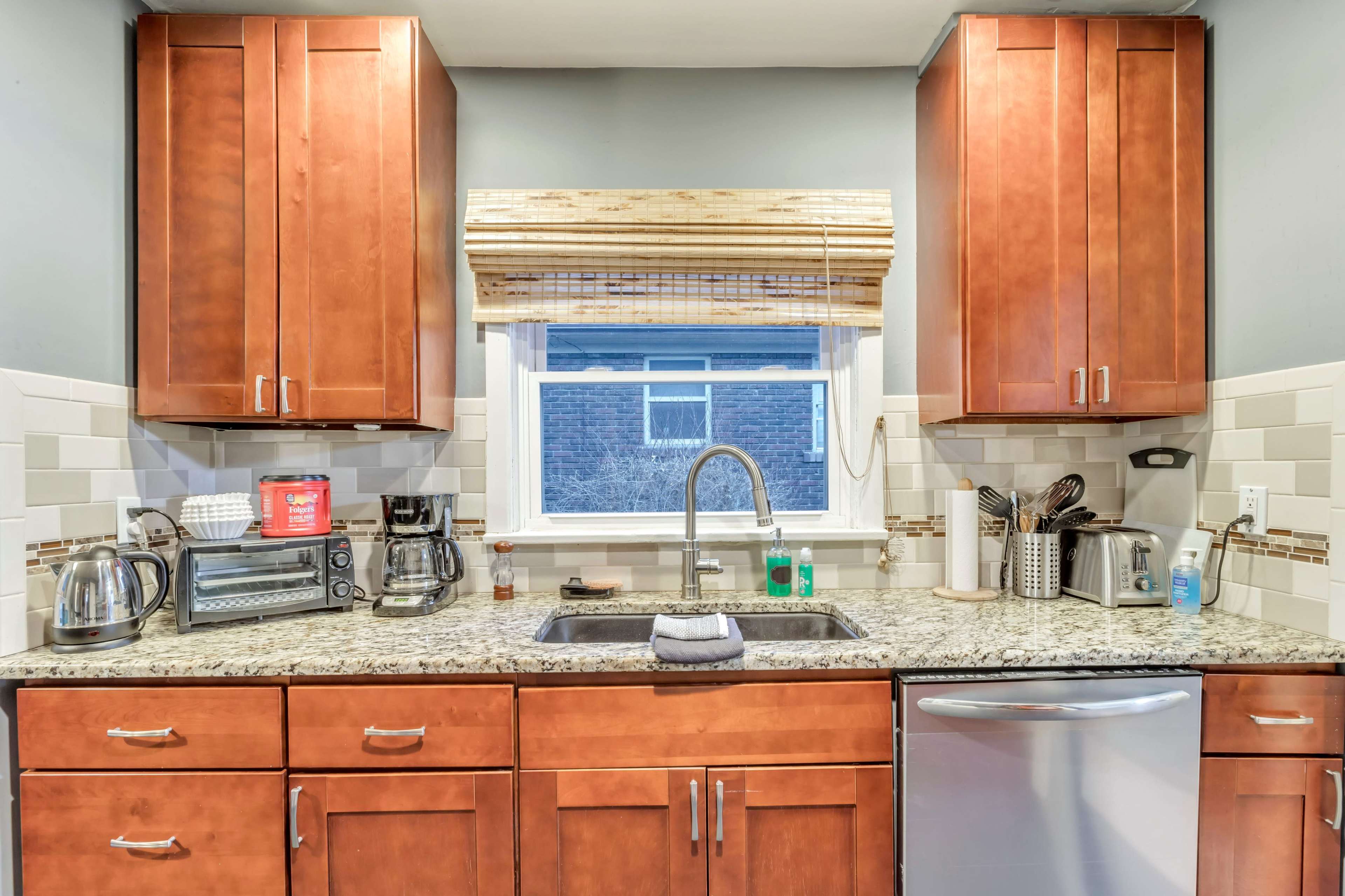 A modern kitchen features wooden cabinets, a stainless steel sink, and various appliances arranged neatly on the countertop.