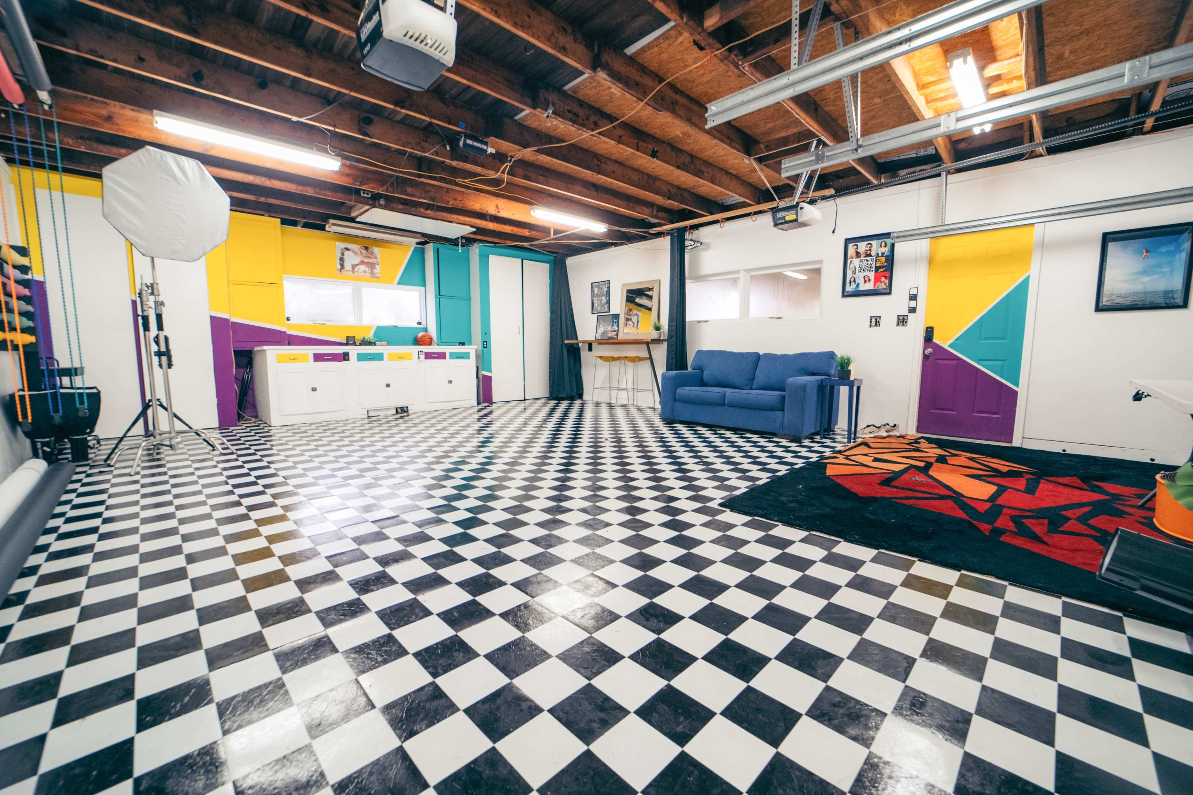 The room features a checkered floor, brightly colored walls, and a blue couch against one wall.