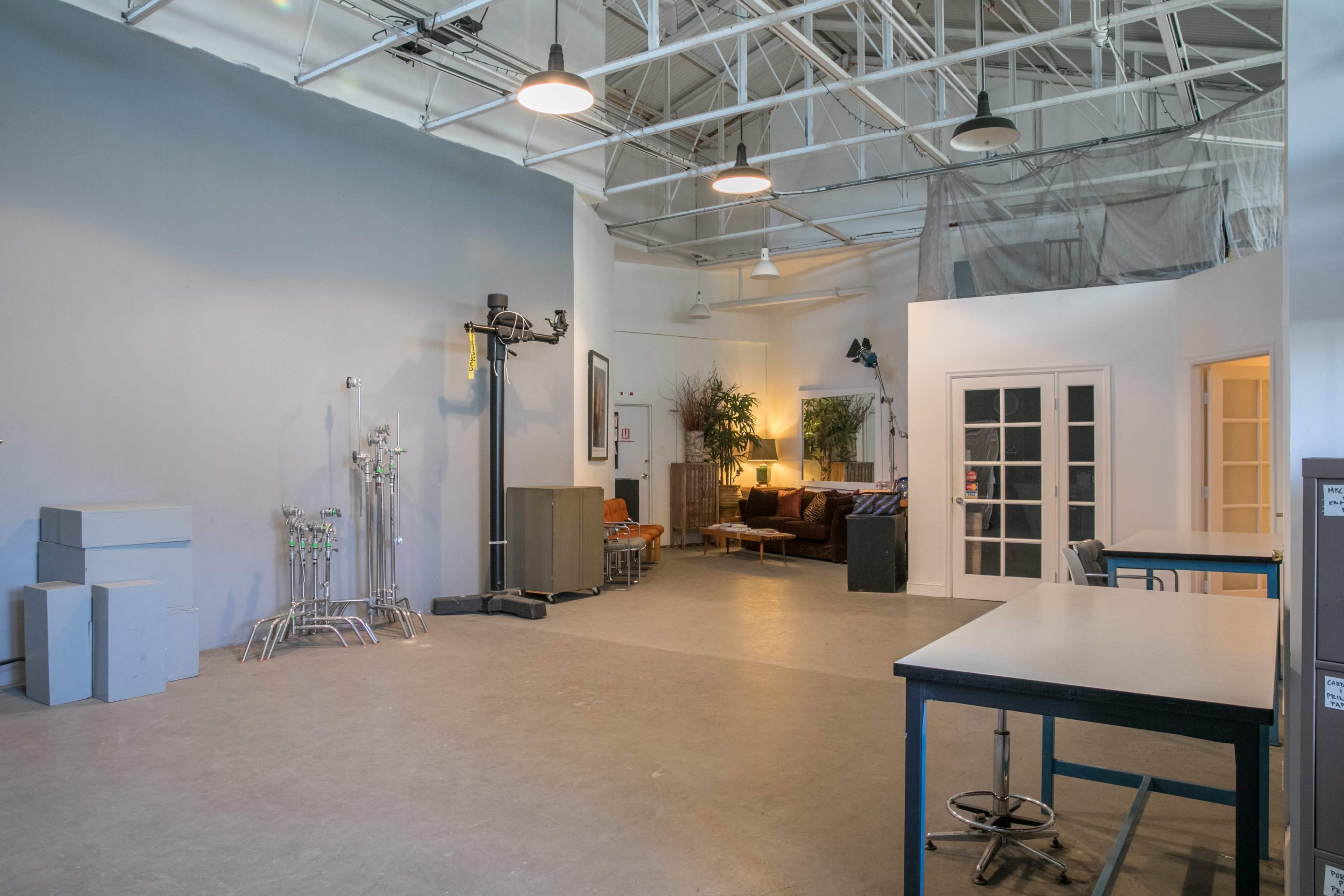 A spacious, well-lit studio with a seating area, medical equipment on one side, and multiple tables arranged in the open space.