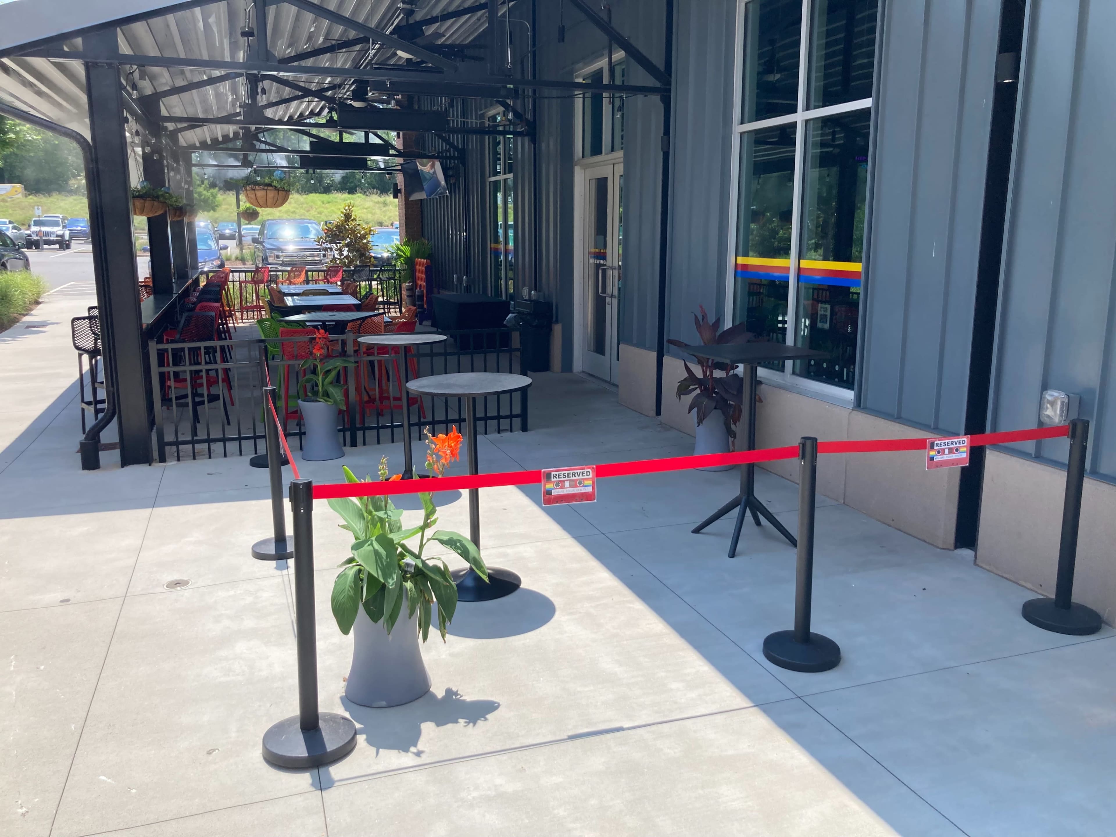 An outdoor dining area of a restaurant with tables and chairs separated by a red barrier tape.