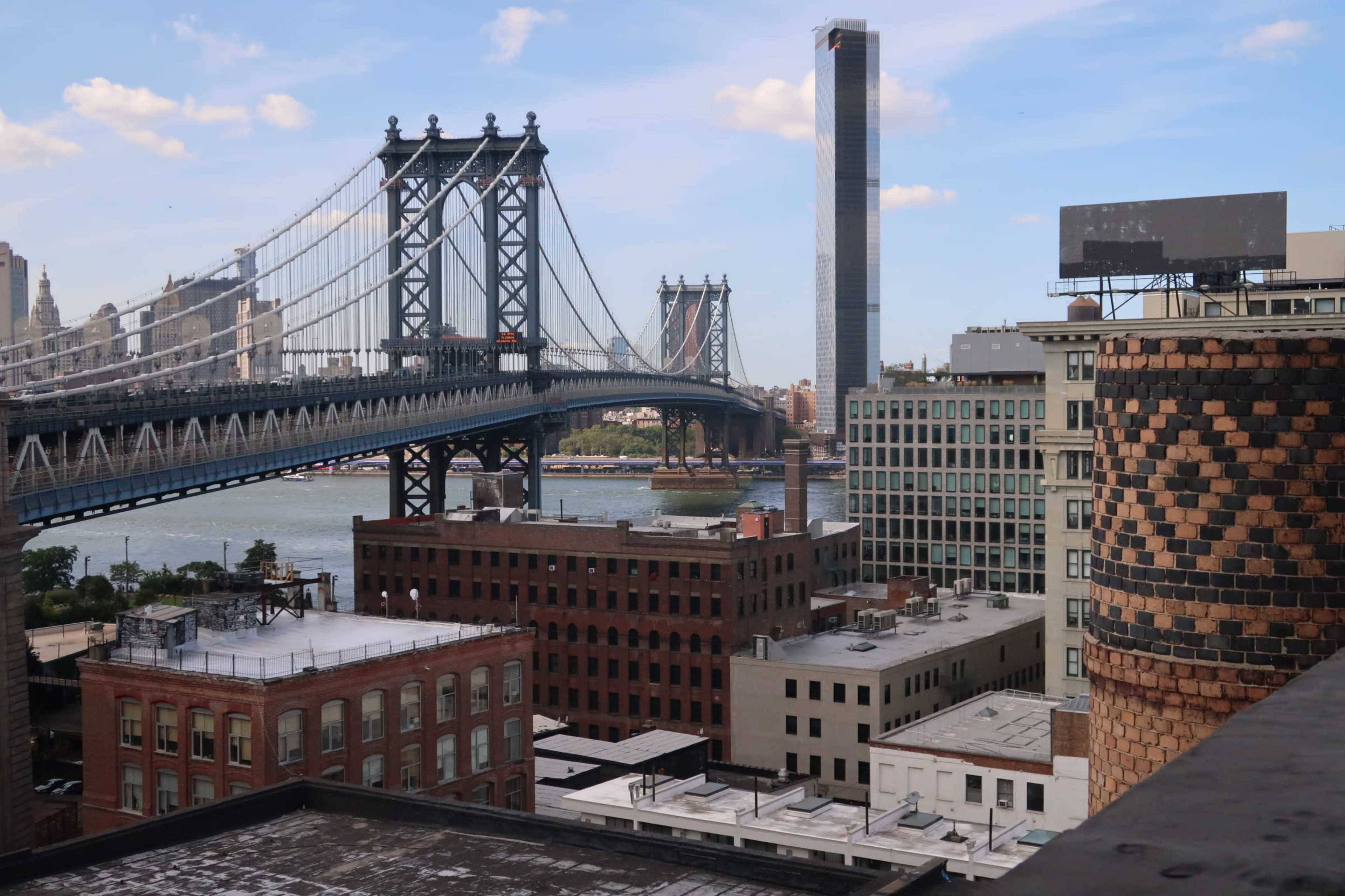 The Manhattan Bridge connecting two urban landscapes with buildings and the East River in the background.