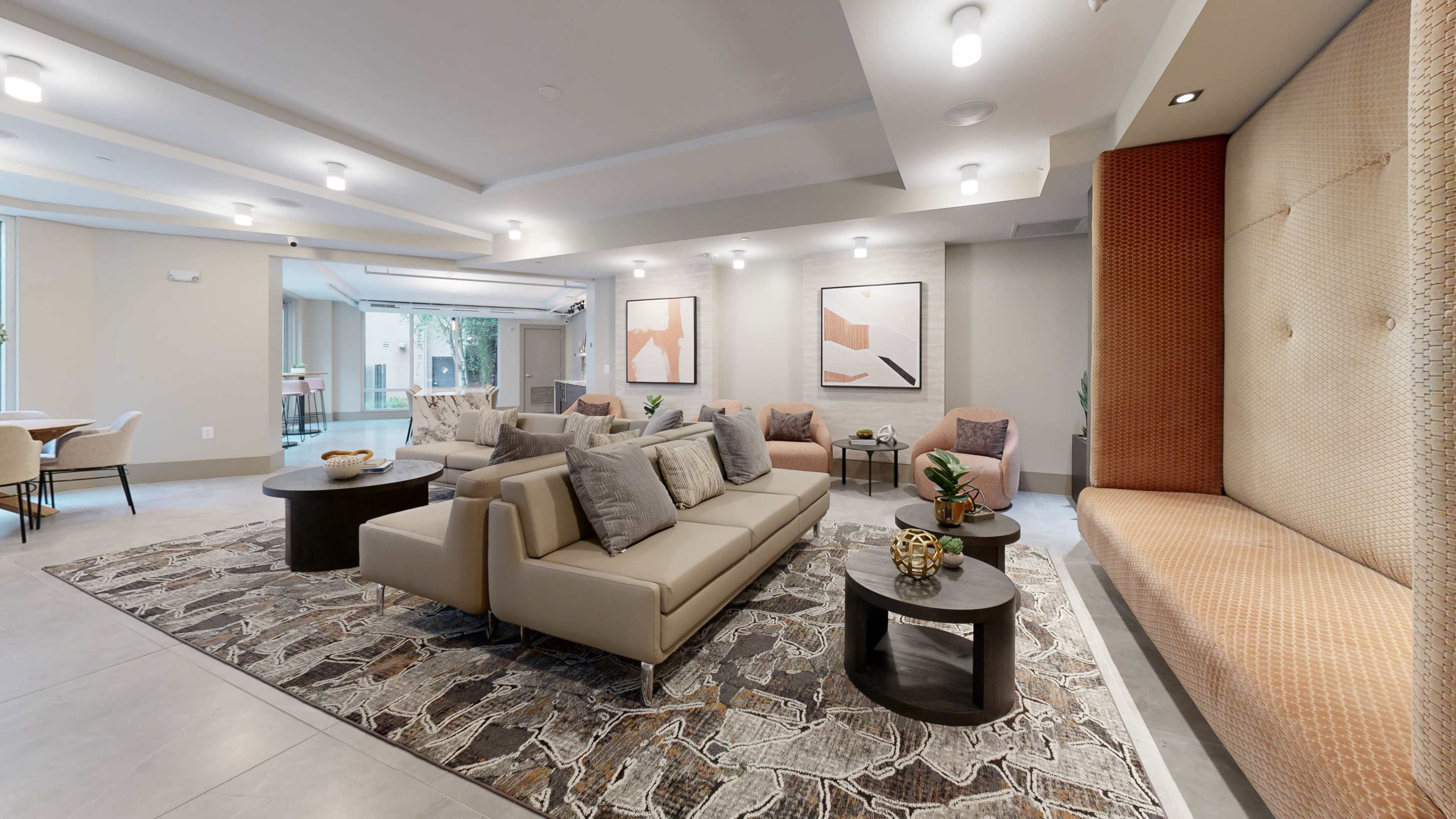A modern lounge area with beige sofas, round tables, and decorative artwork on the walls.