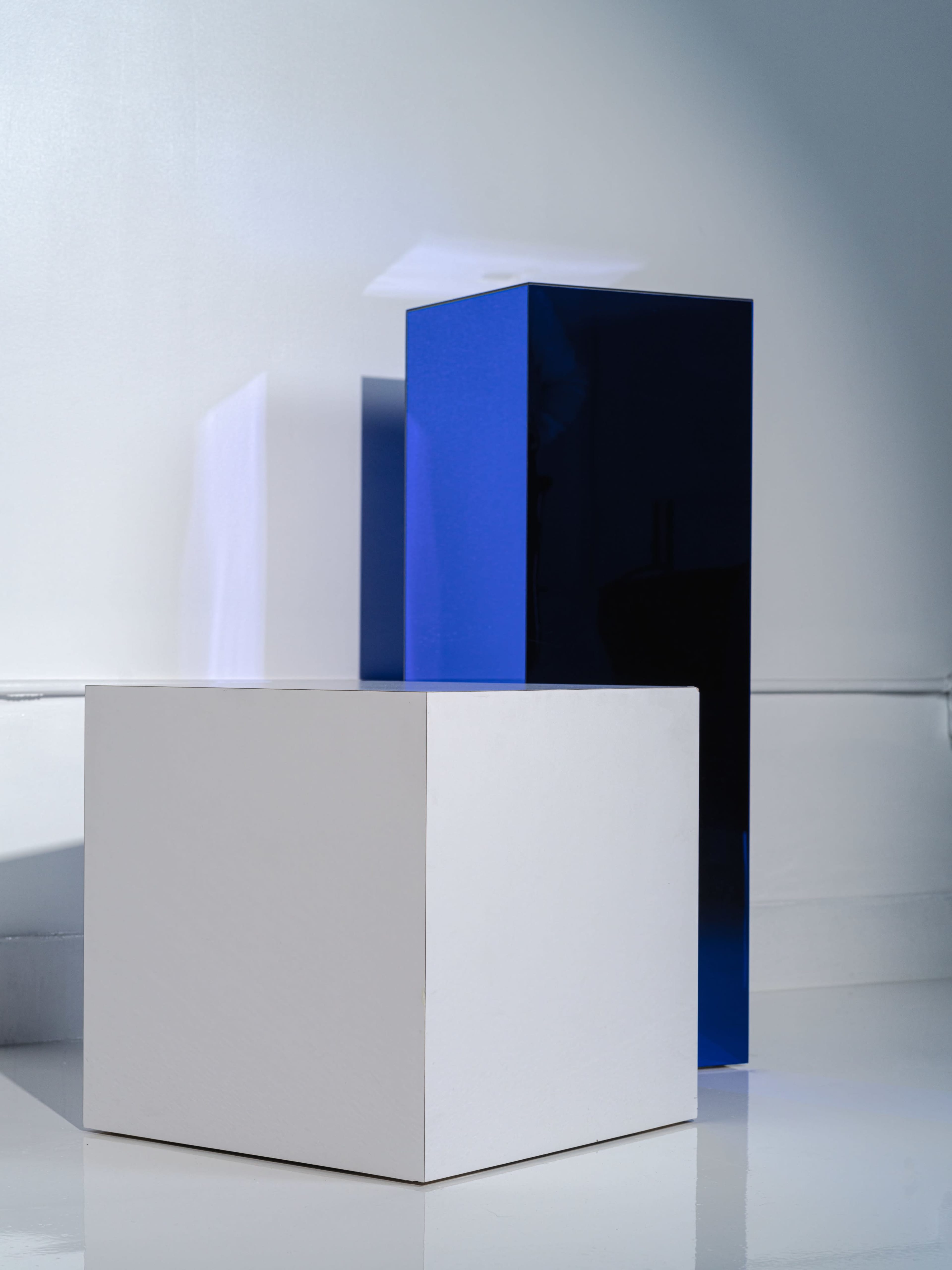 The image shows two geometric blocks, one white and one dark blue, positioned against a light backdrop.