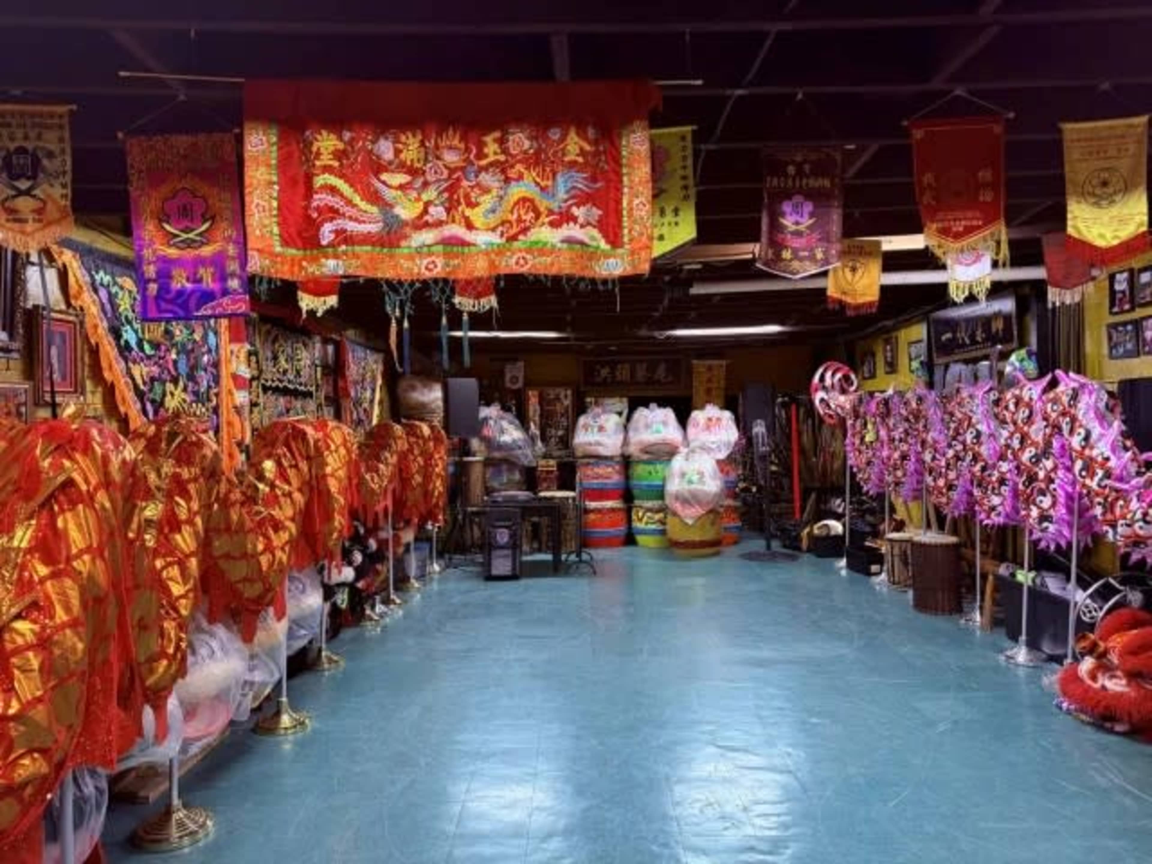 The image shows a spacious room decorated with colorful traditional banners and ornate costumes, with various items related to cultural performance lining the walls.