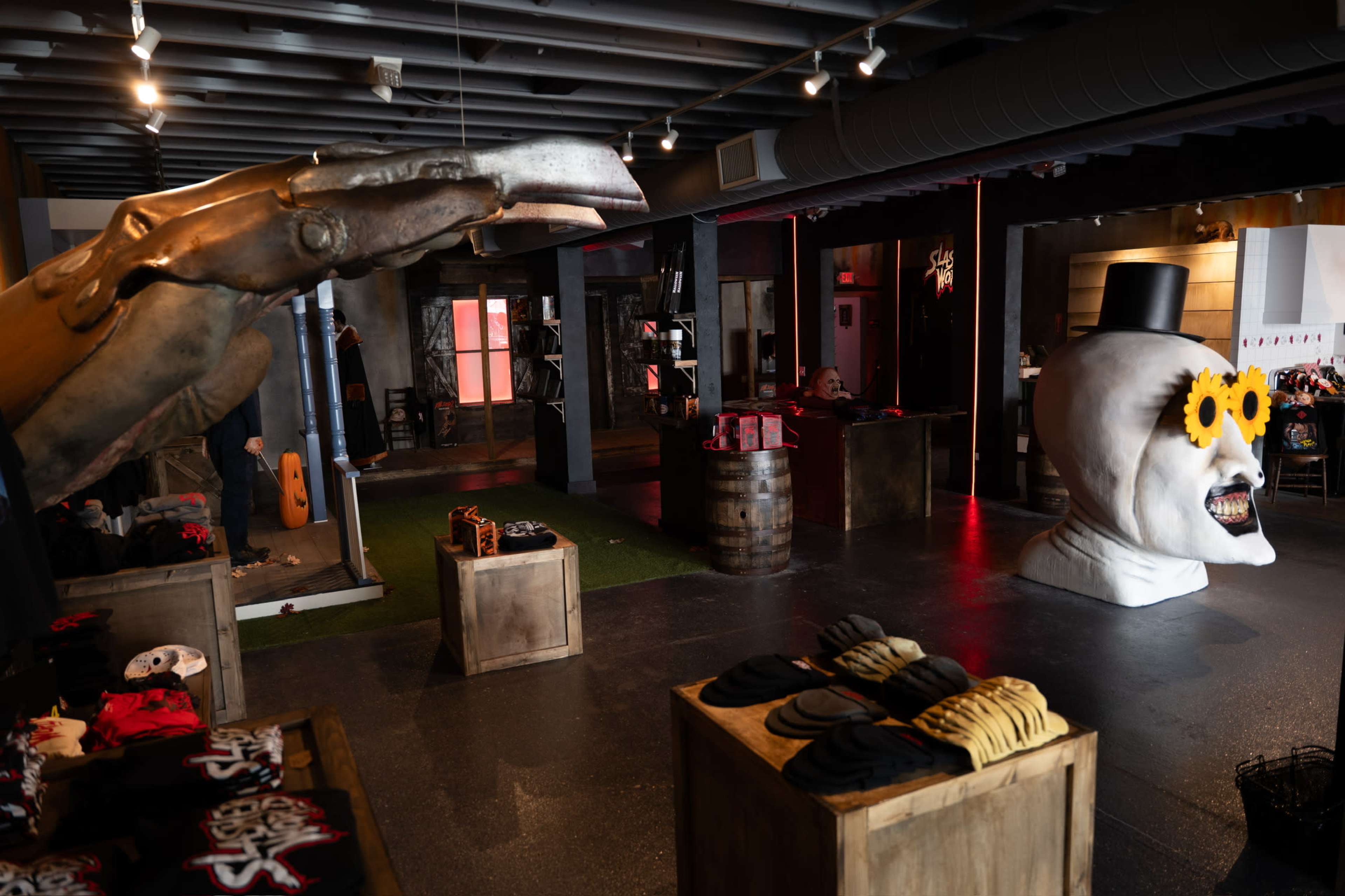 The interior of a themed retail space features unique sculptures, including a large hand and a stylized skull, along with various merchandise displays.